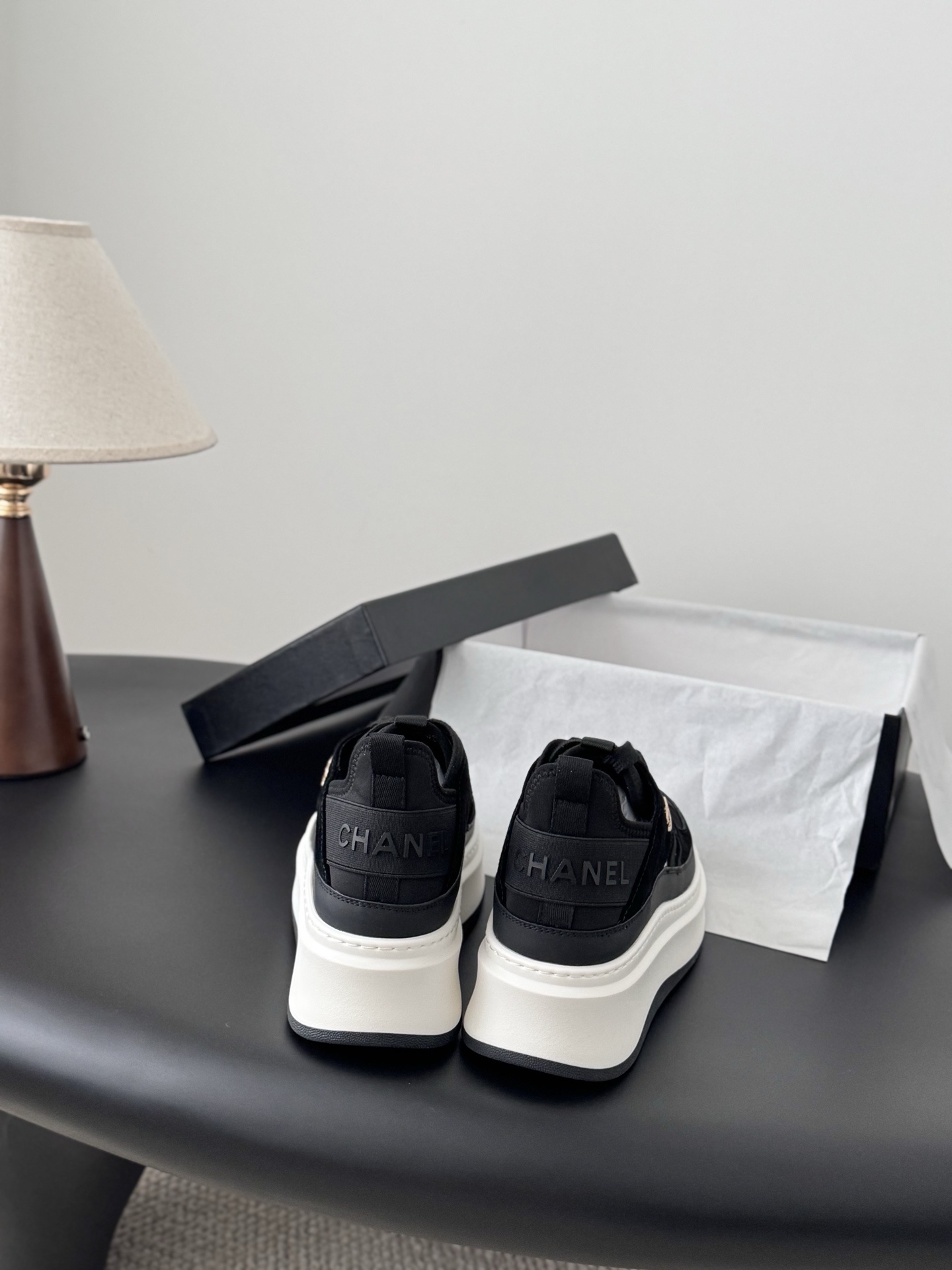 A pair of Chanel black suede and fabric sneakers with chunky white platform soles and gold CC logo next to a branded Chanel box. - Hình 5