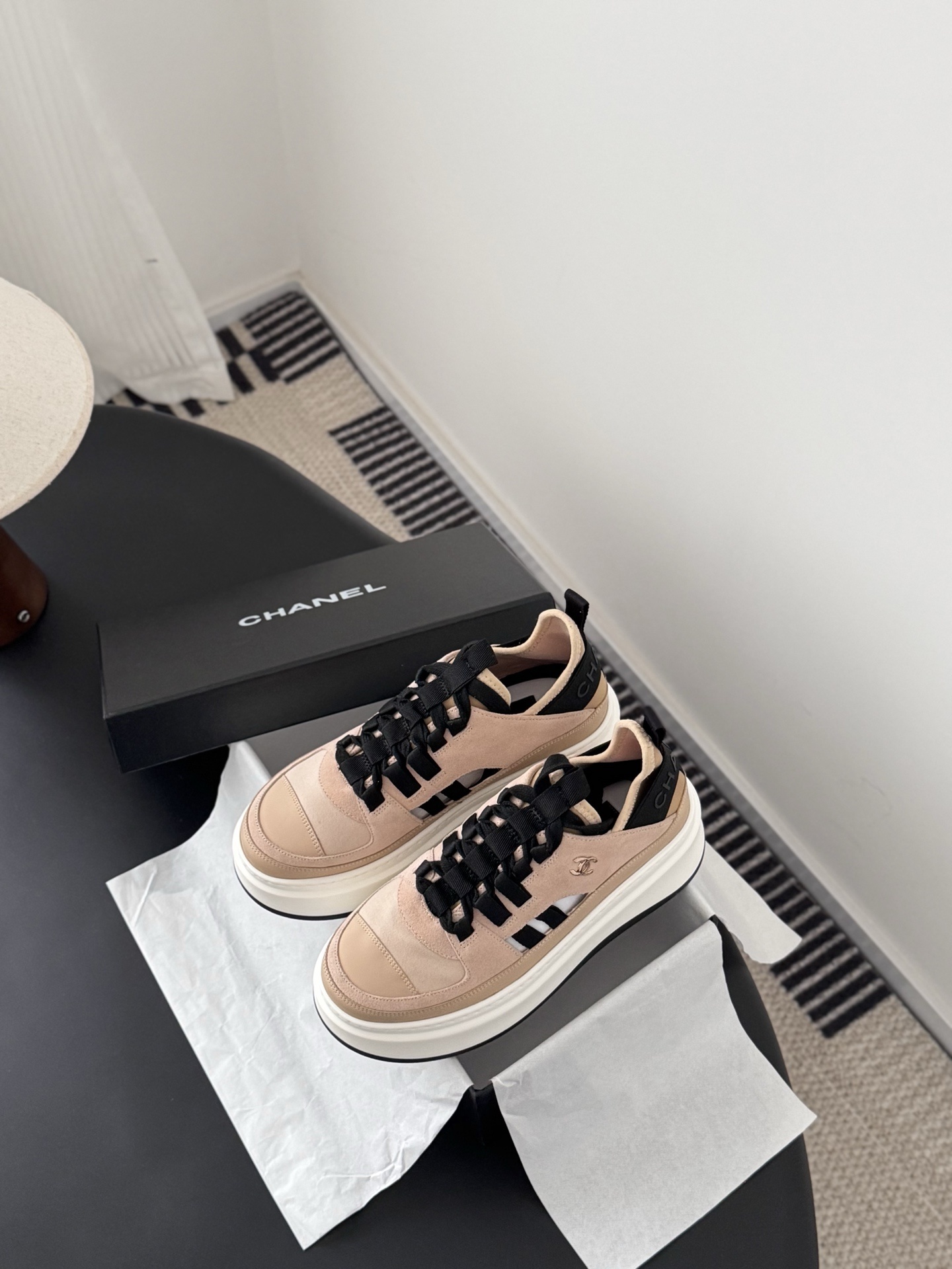 Chanel beige and black leather platform sneakers with chunky white soles displayed next to a black Chanel shoe box. - Hình 6