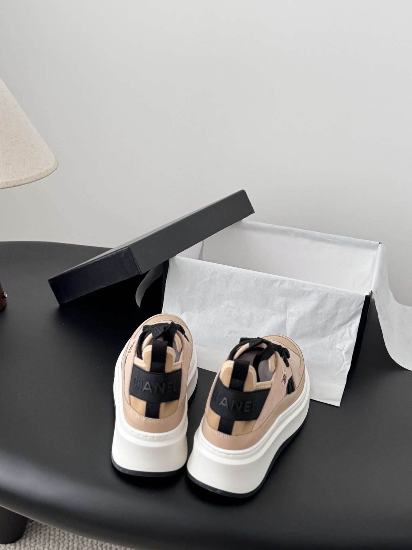 Chanel beige and black leather platform sneakers with chunky white soles displayed next to a black Chanel shoe box. - Hình 5