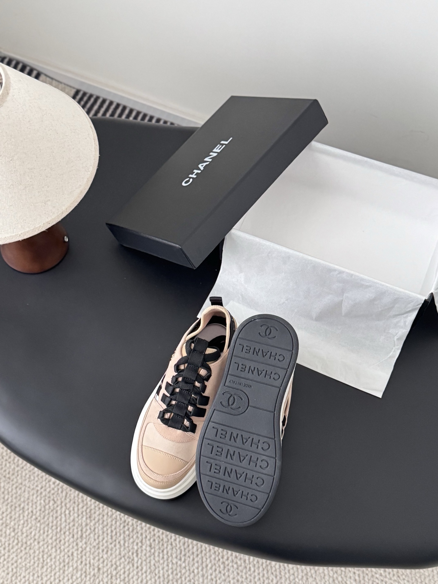Chanel beige and black leather platform sneakers with chunky white soles displayed next to a black Chanel shoe box. - Hình 4