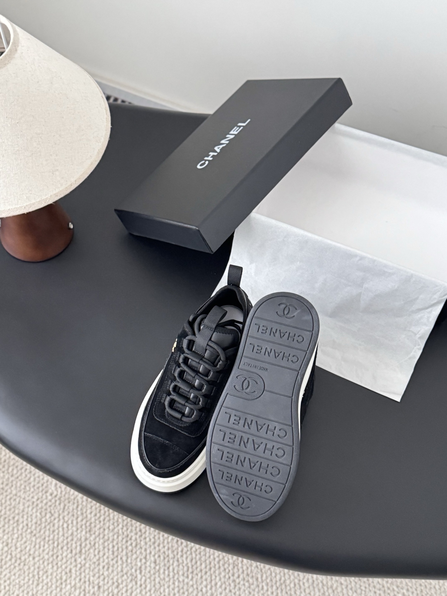 Pair of black Chanel suede platform sneakers with chunky white soles and gold CC logo next to a Chanel shoe box - Hình 4