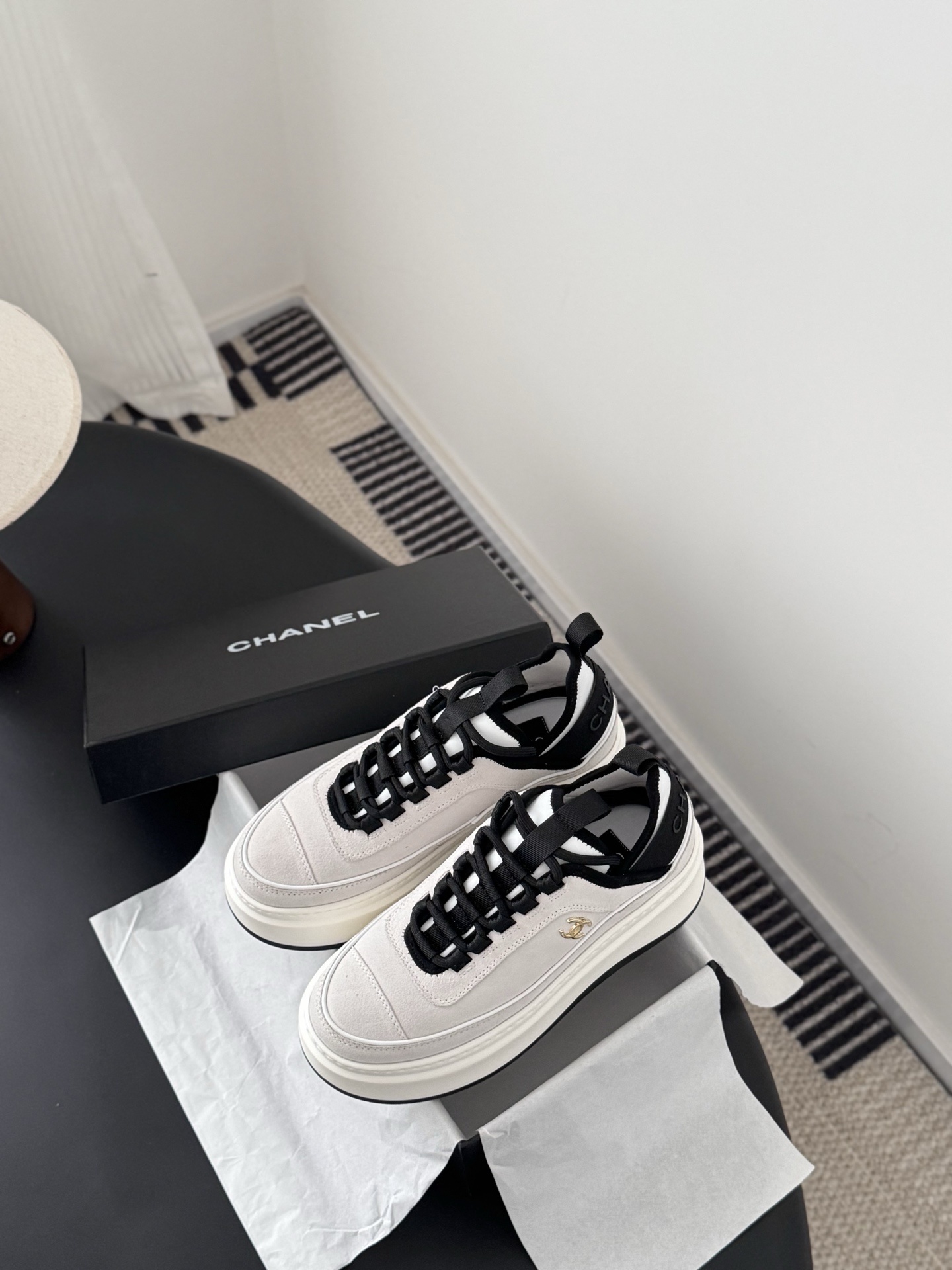 Luxury Chanel platform sneakers in off-white and black with gold CC logo detail on a black table with box. - Hình 6