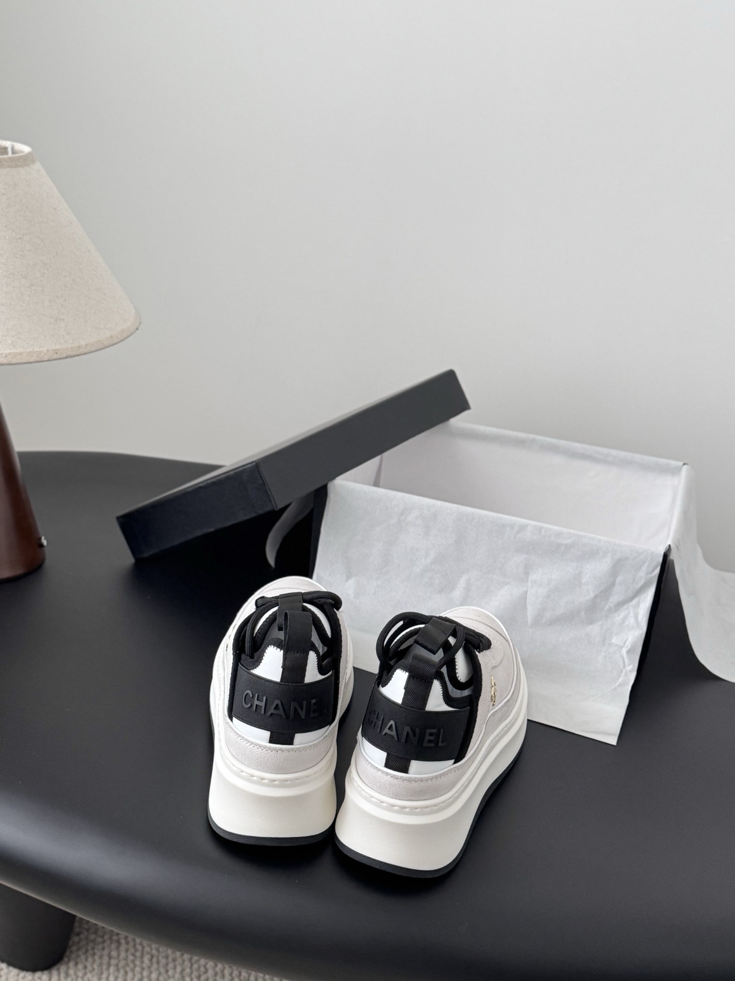 Luxury Chanel platform sneakers in off-white and black with gold CC logo detail on a black table with box. - Hình 5