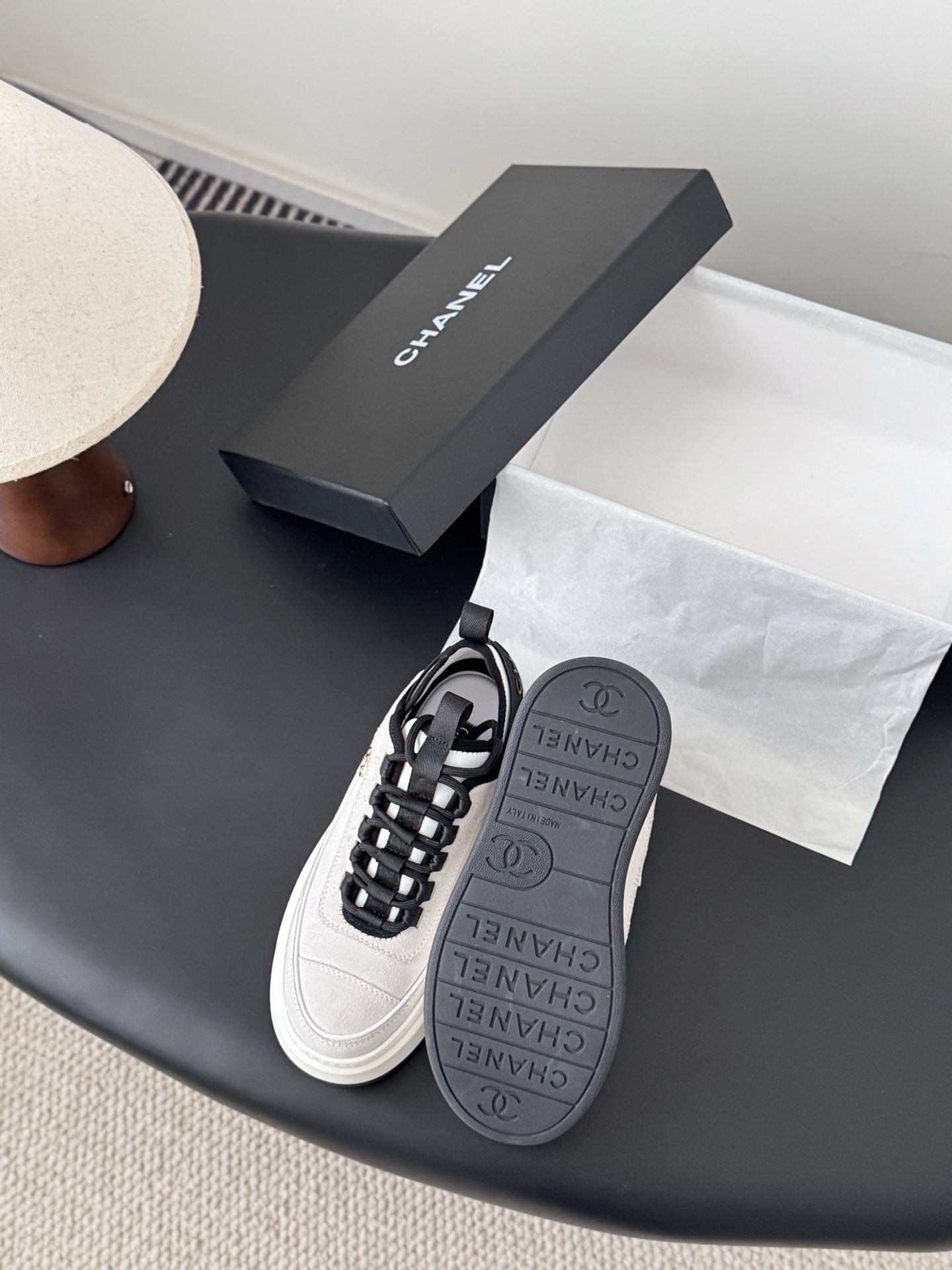 Luxury Chanel platform sneakers in off-white and black with gold CC logo detail on a black table with box. - Hình 4
