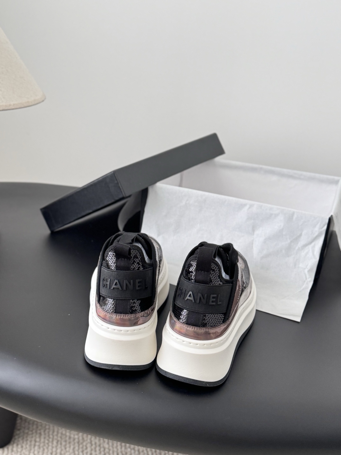 Pair of luxury Chanel platform sneakers with iridescent pink and black sequin details next to a black Chanel box - Hình 5