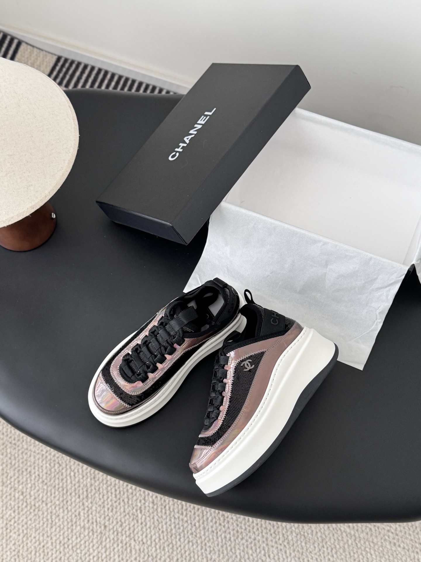 Pair of luxury Chanel platform sneakers with iridescent pink and black sequin details next to a black Chanel box - Hình 3
