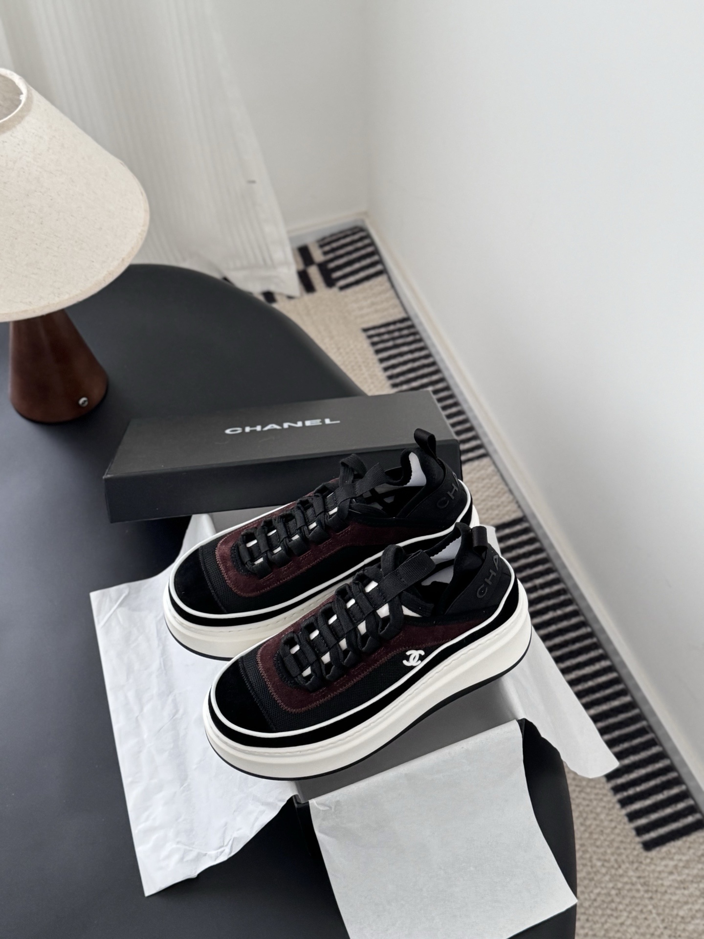 A pair of black and burgundy Chanel platform sneakers next to their original black box - Hình 6