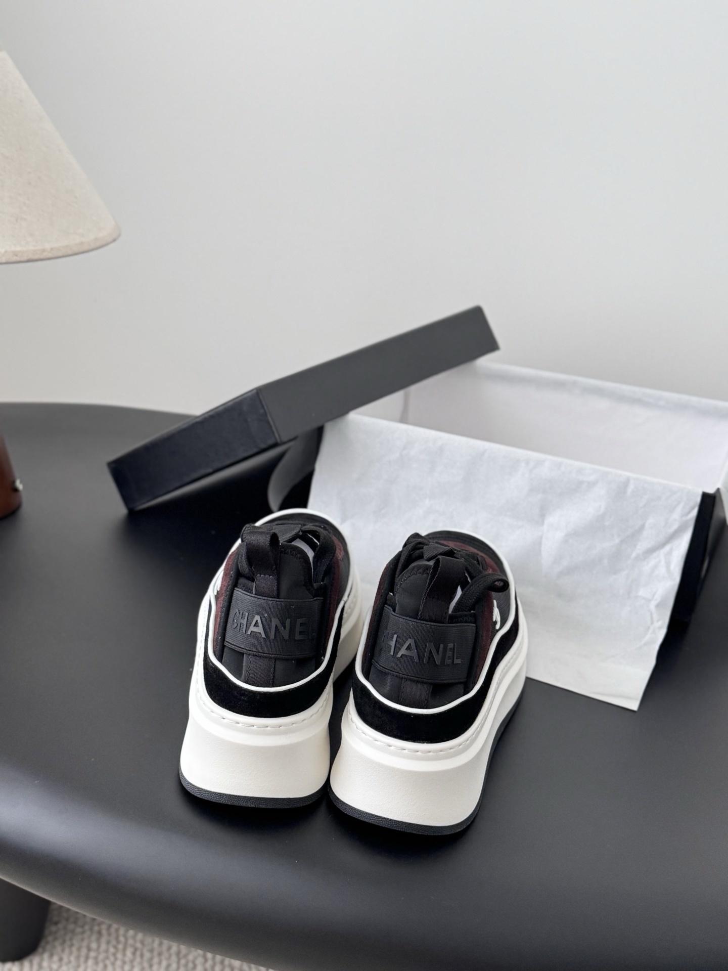 A pair of black and burgundy Chanel platform sneakers next to their original black box - Hình 5