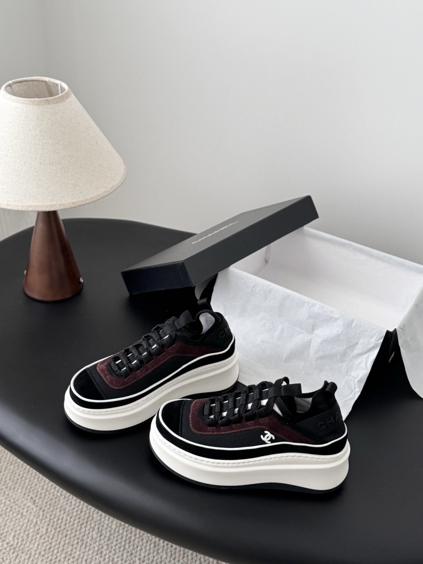 A pair of black and burgundy Chanel platform sneakers next to their original black box - Hình 2