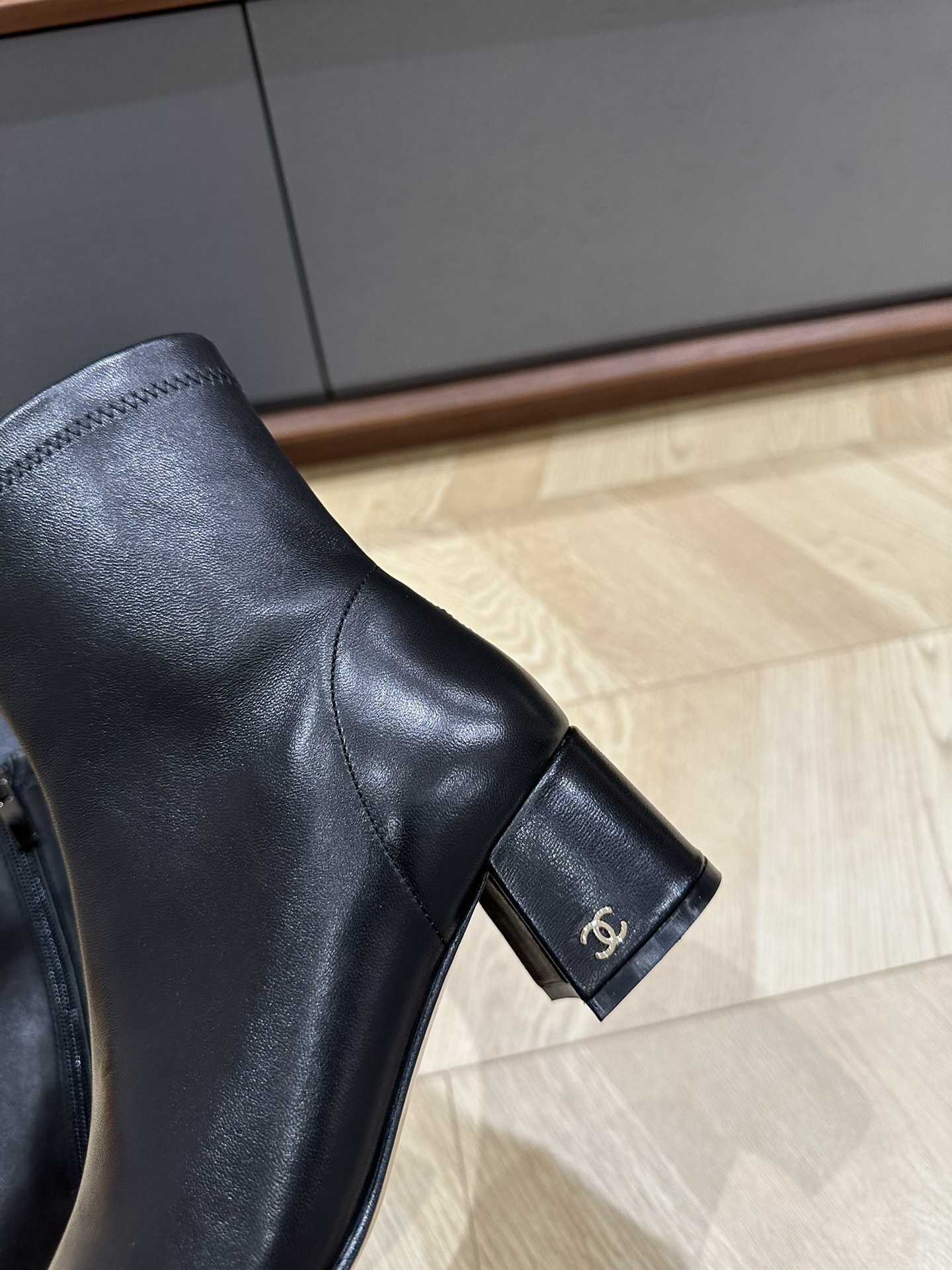 A pair of Chanel black leather ankle boots with grosgrain cap toes and silver CC logo on the block heel, displayed on a Chanel shoe box. - Hình 6