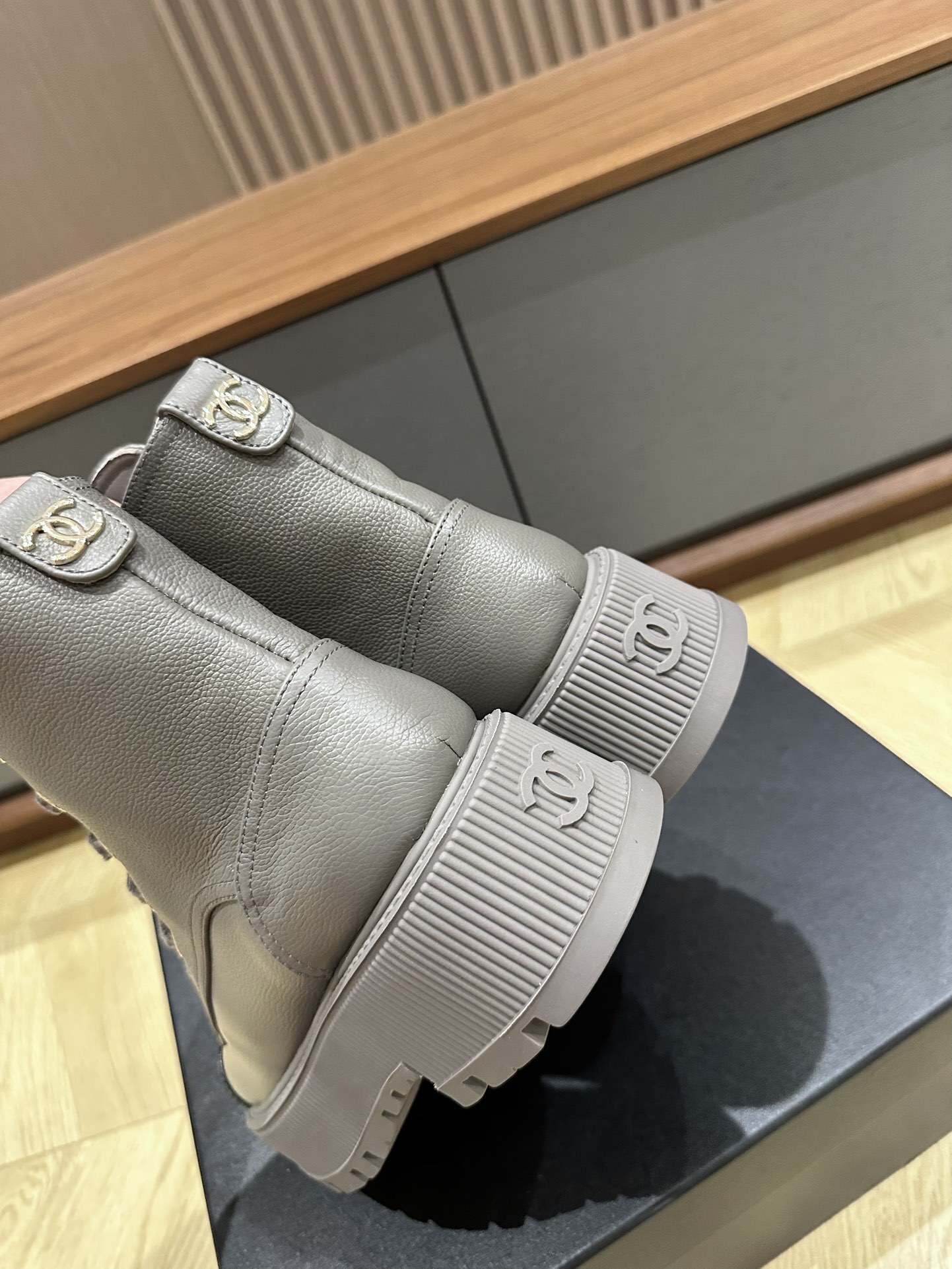 Luxury Chanel grey leather ankle boots with black patent toe cap and gold brand lettering on a black box. - Hình 7