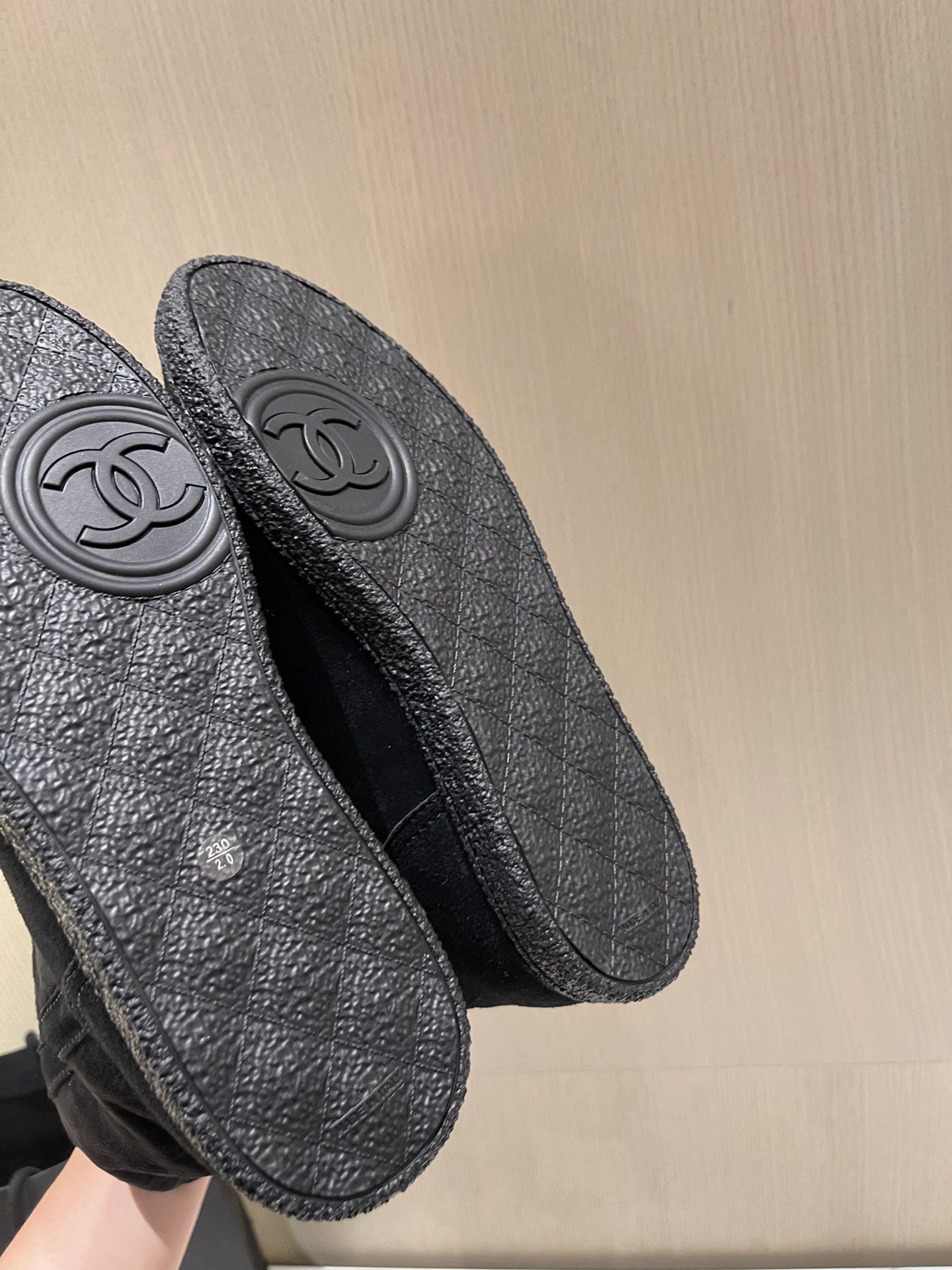 Pair of Chanel black quilted suede mid-calf winter boots with fur lining and gold CC logo displayed on a marble surface. - Hình 9