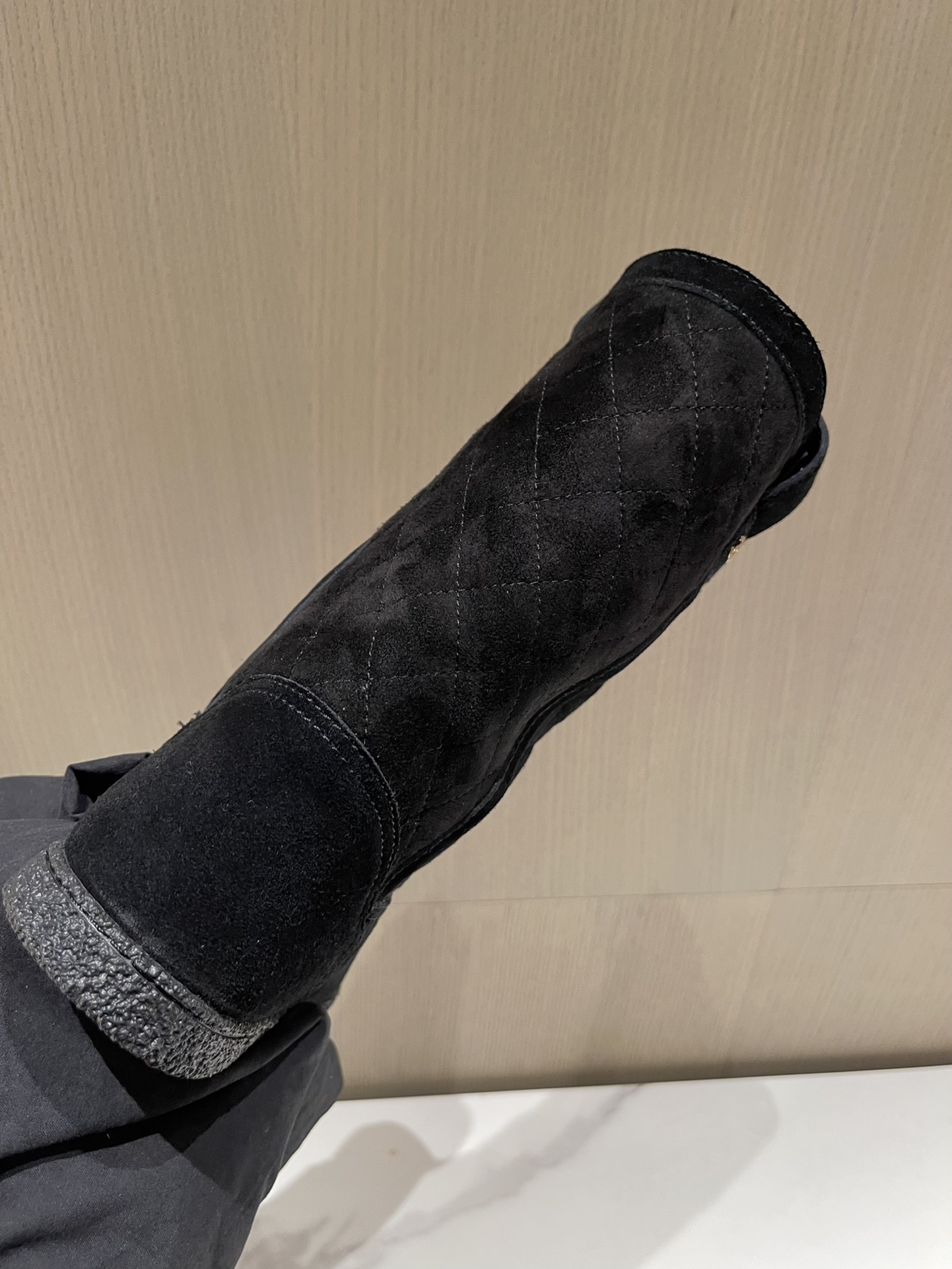 Pair of Chanel black quilted suede mid-calf winter boots with fur lining and gold CC logo displayed on a marble surface. - Hình 8