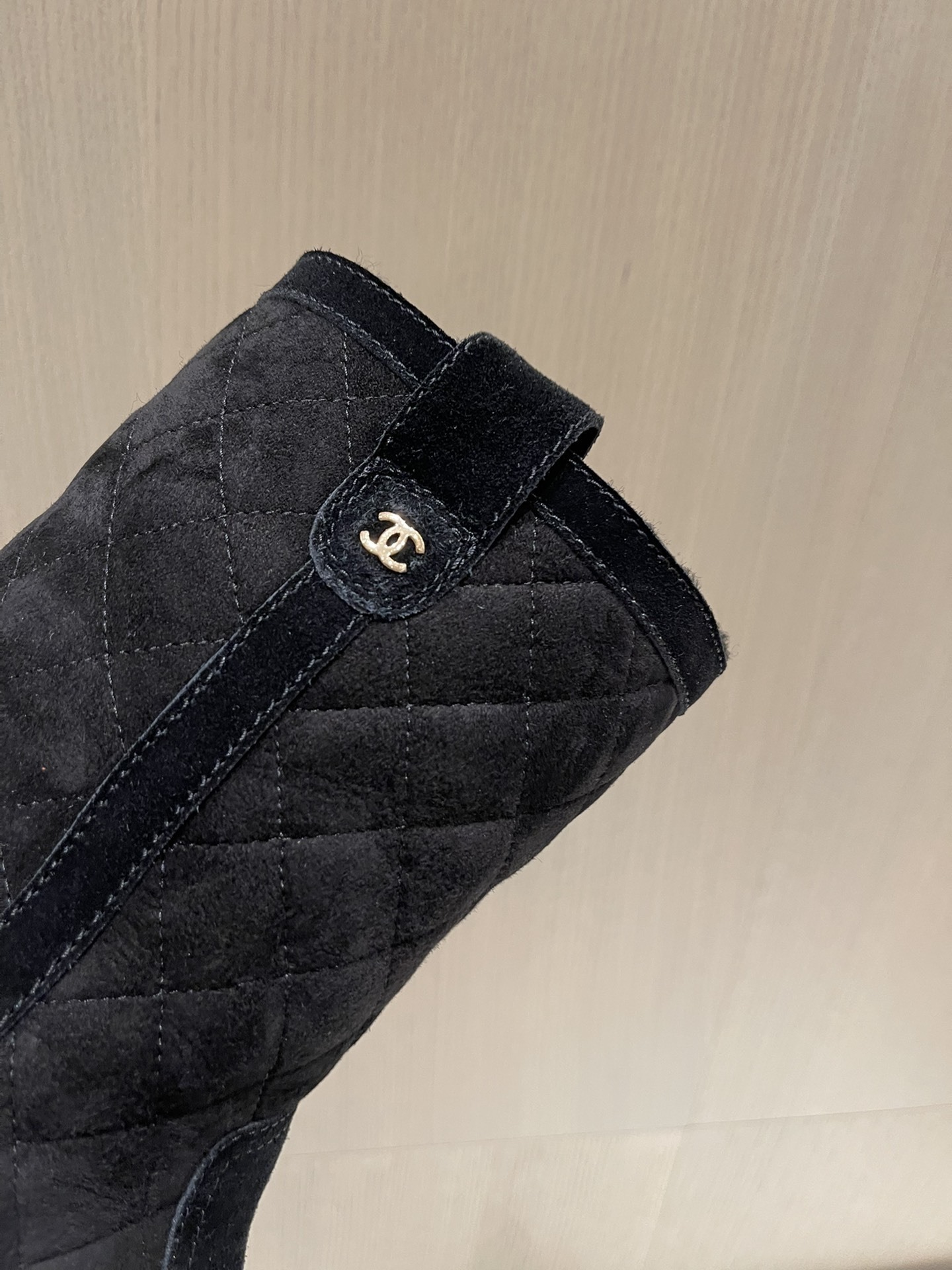 Pair of Chanel black quilted suede mid-calf winter boots with fur lining and gold CC logo displayed on a marble surface. - Hình 6