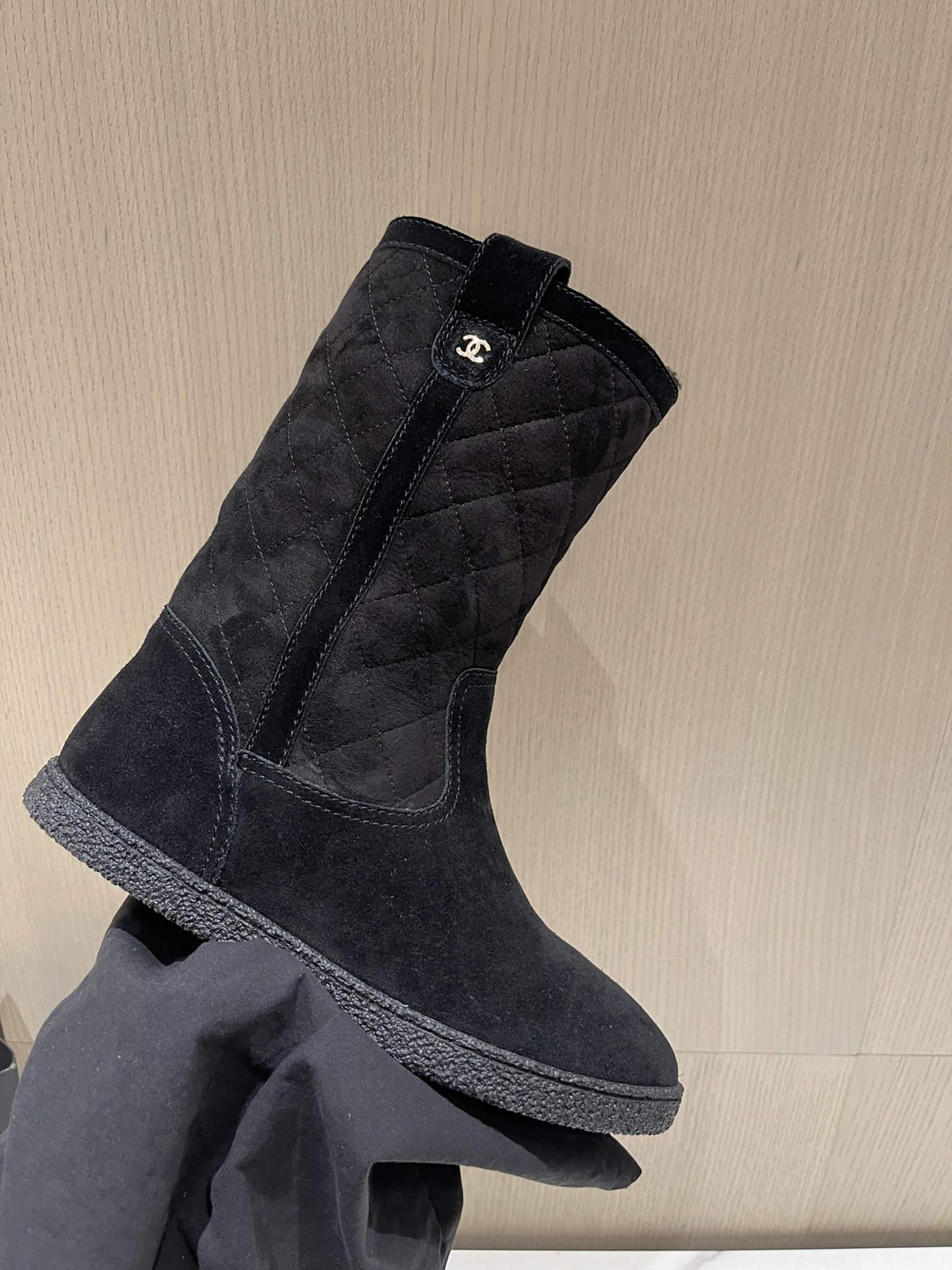 Pair of Chanel black quilted suede mid-calf winter boots with fur lining and gold CC logo displayed on a marble surface. - Hình 5