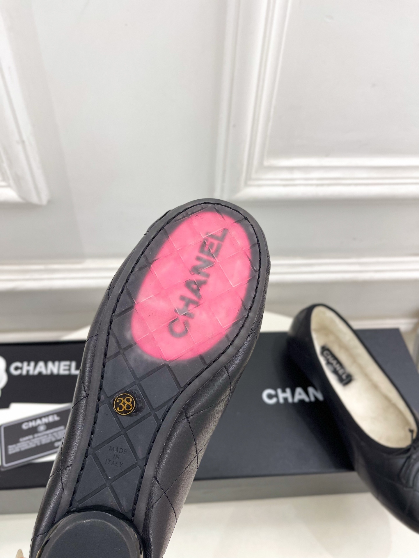 Pair of black Chanel quilted leather ballet flats with white fur lining and CC logo on a table - Hình 9
