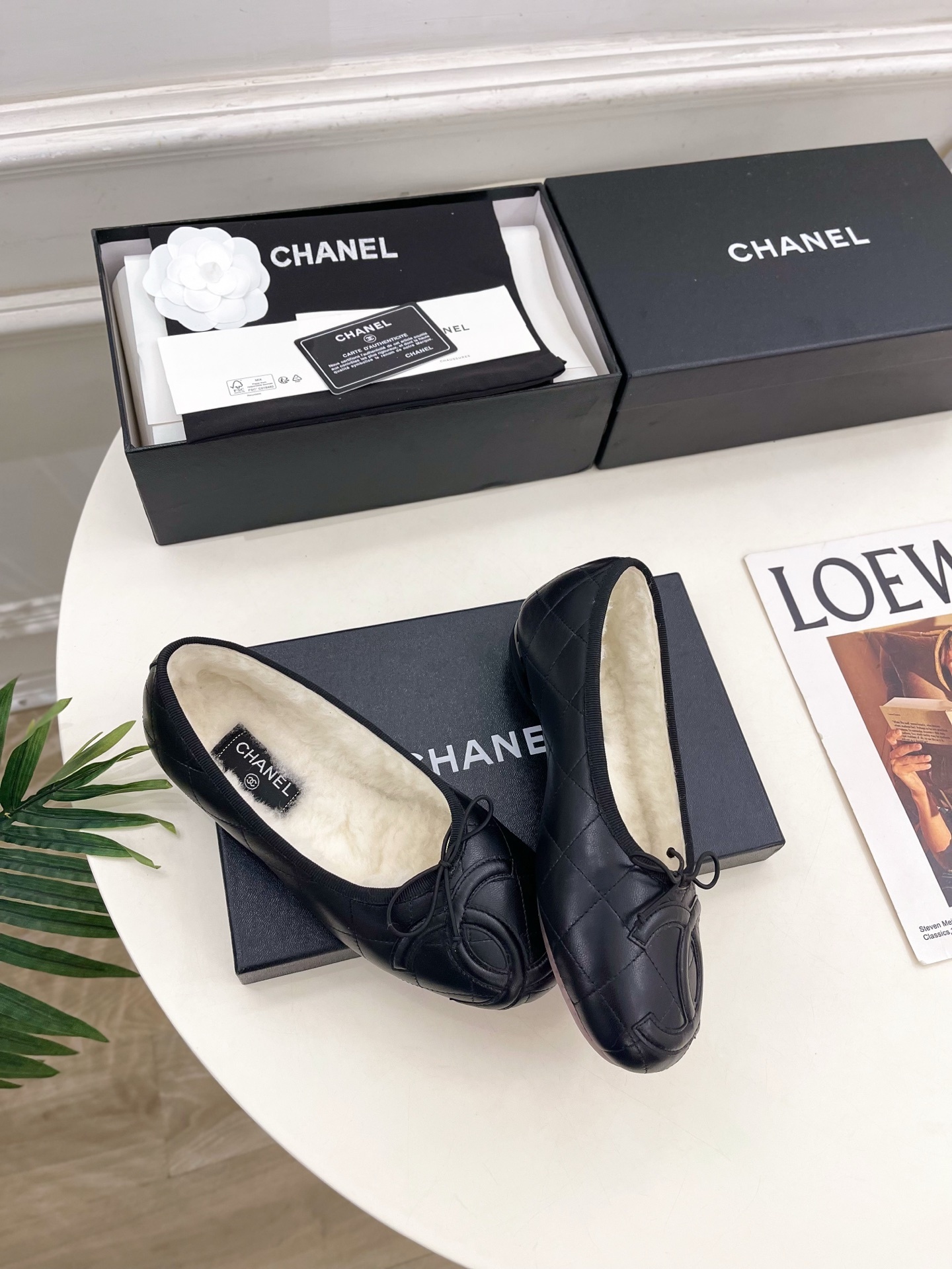 Pair of black Chanel quilted leather ballet flats with white fur lining and CC logo on a table - Hình 4