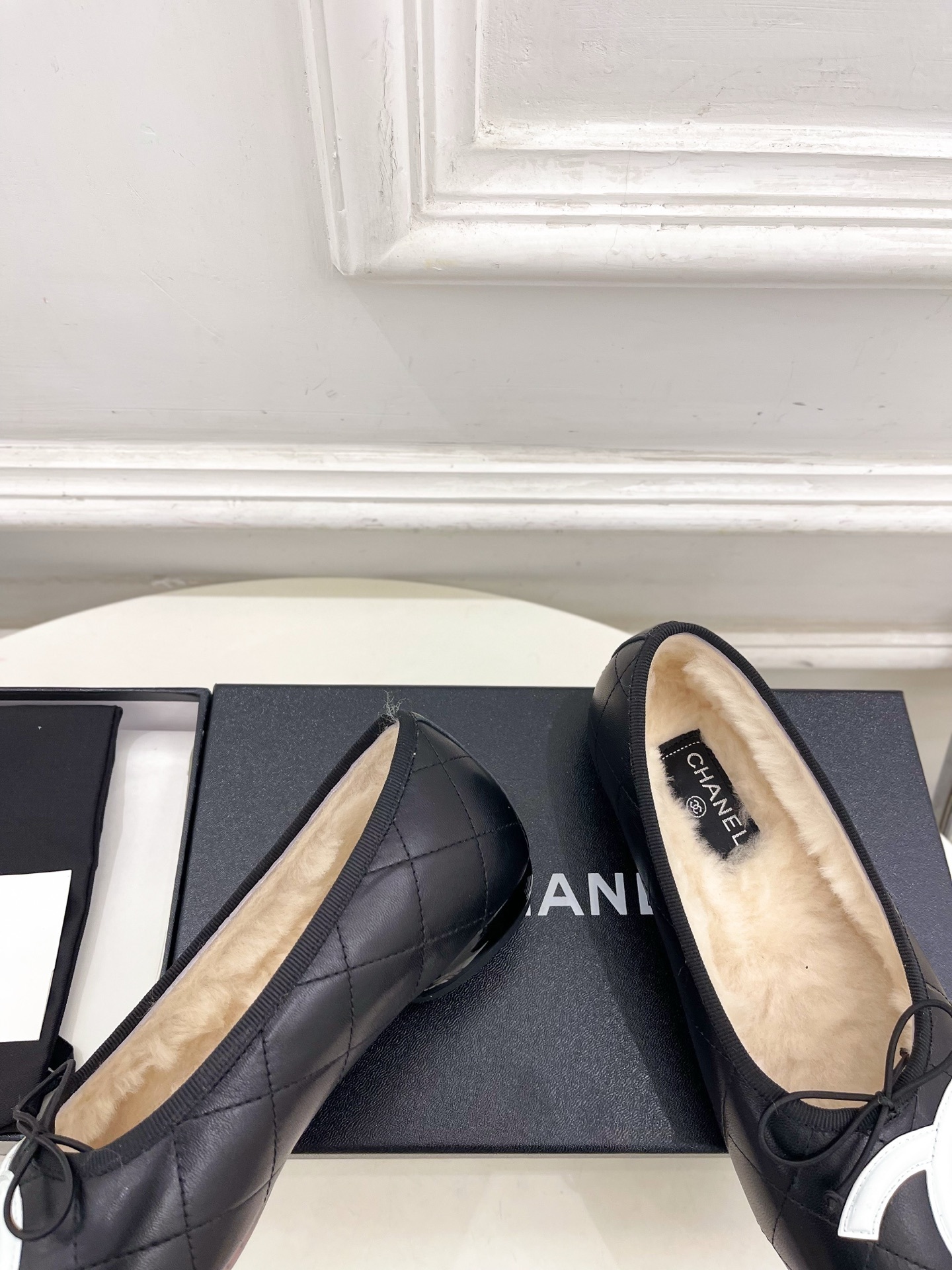 Black Chanel quilted leather ballerina flats with white CC logo and fur lining shown with luxury packaging - Hình 7