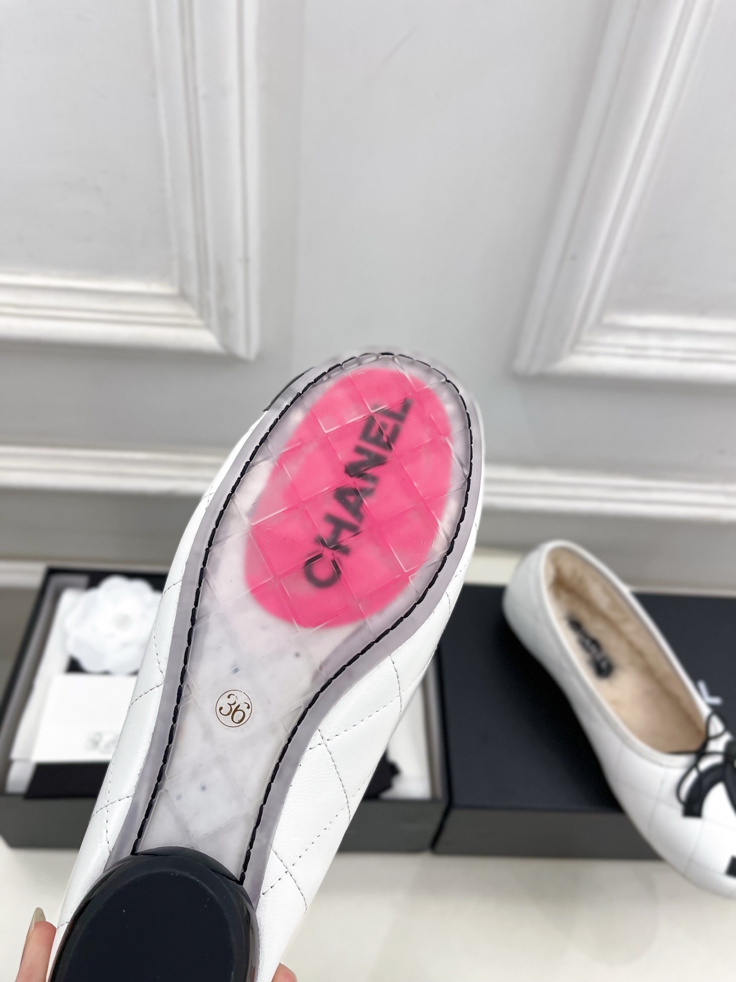 Pair of Chanel white quilted leather ballet flats with black CC logo and shearling lining on a display table. - Hình 9