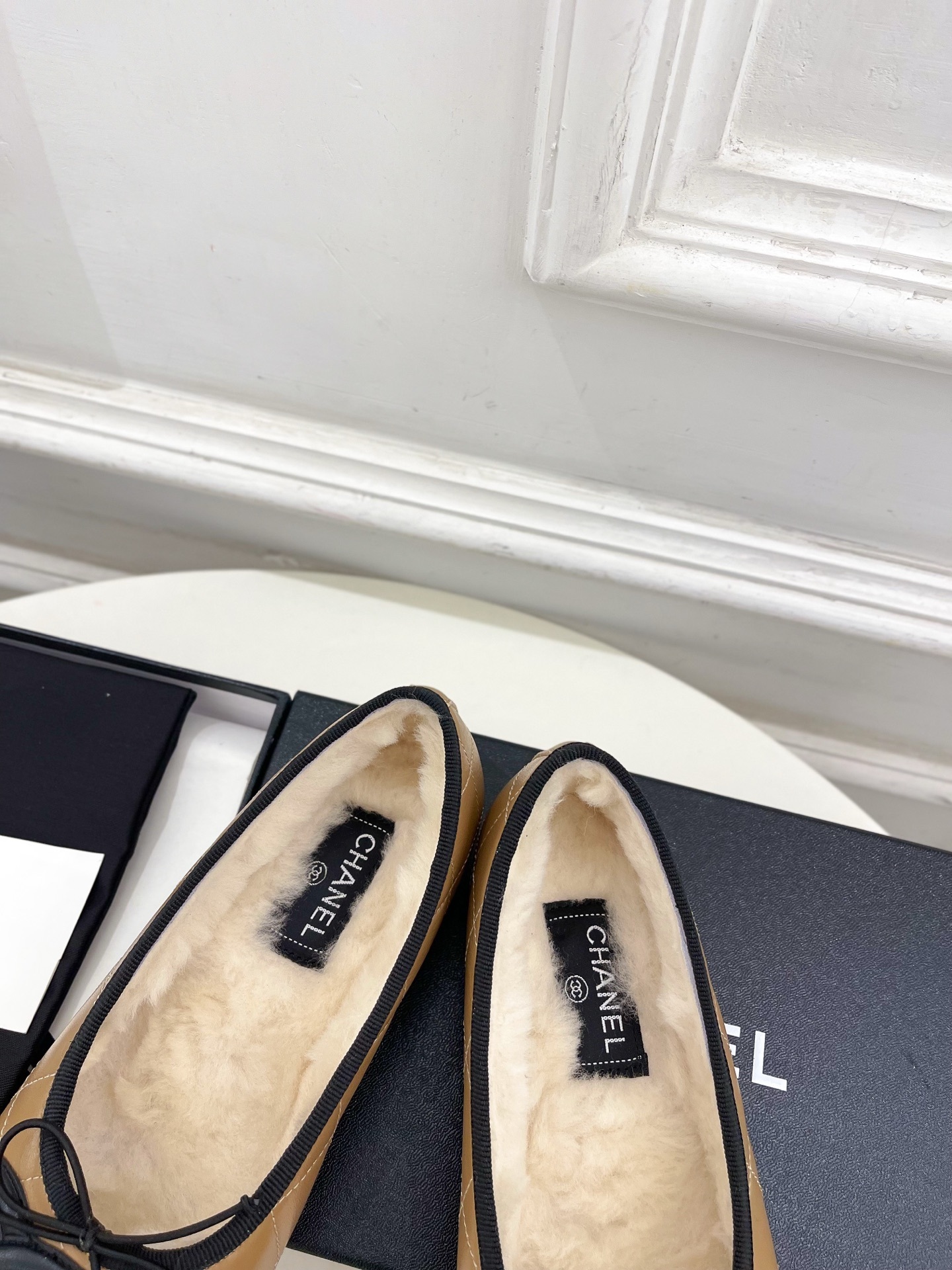 Pair of tan Chanel quilted ballerina flats with black CC logo and fuzzy shearling lining on a white table. - Hình 8