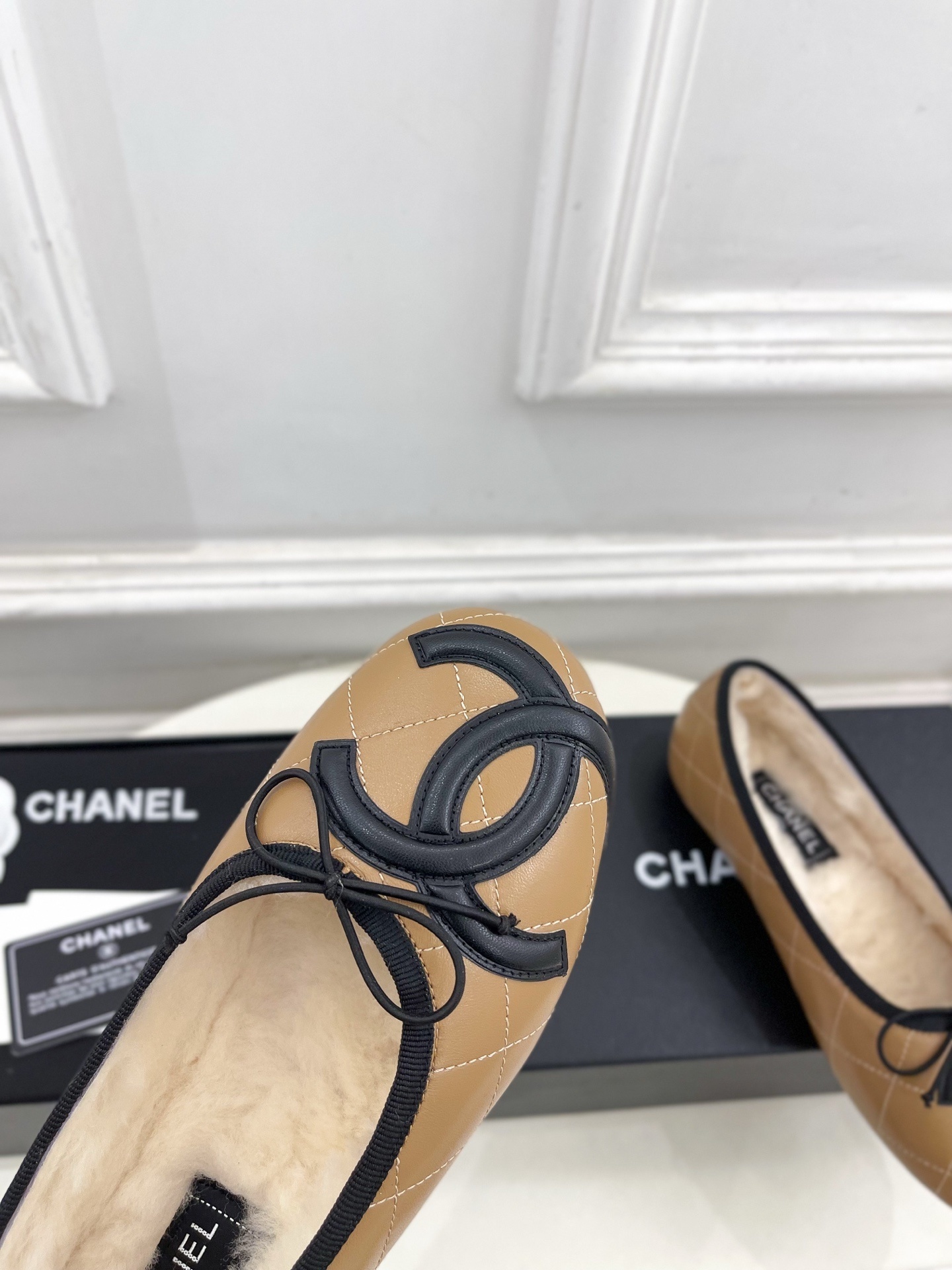 Pair of tan Chanel quilted ballerina flats with black CC logo and fuzzy shearling lining on a white table. - Hình 6