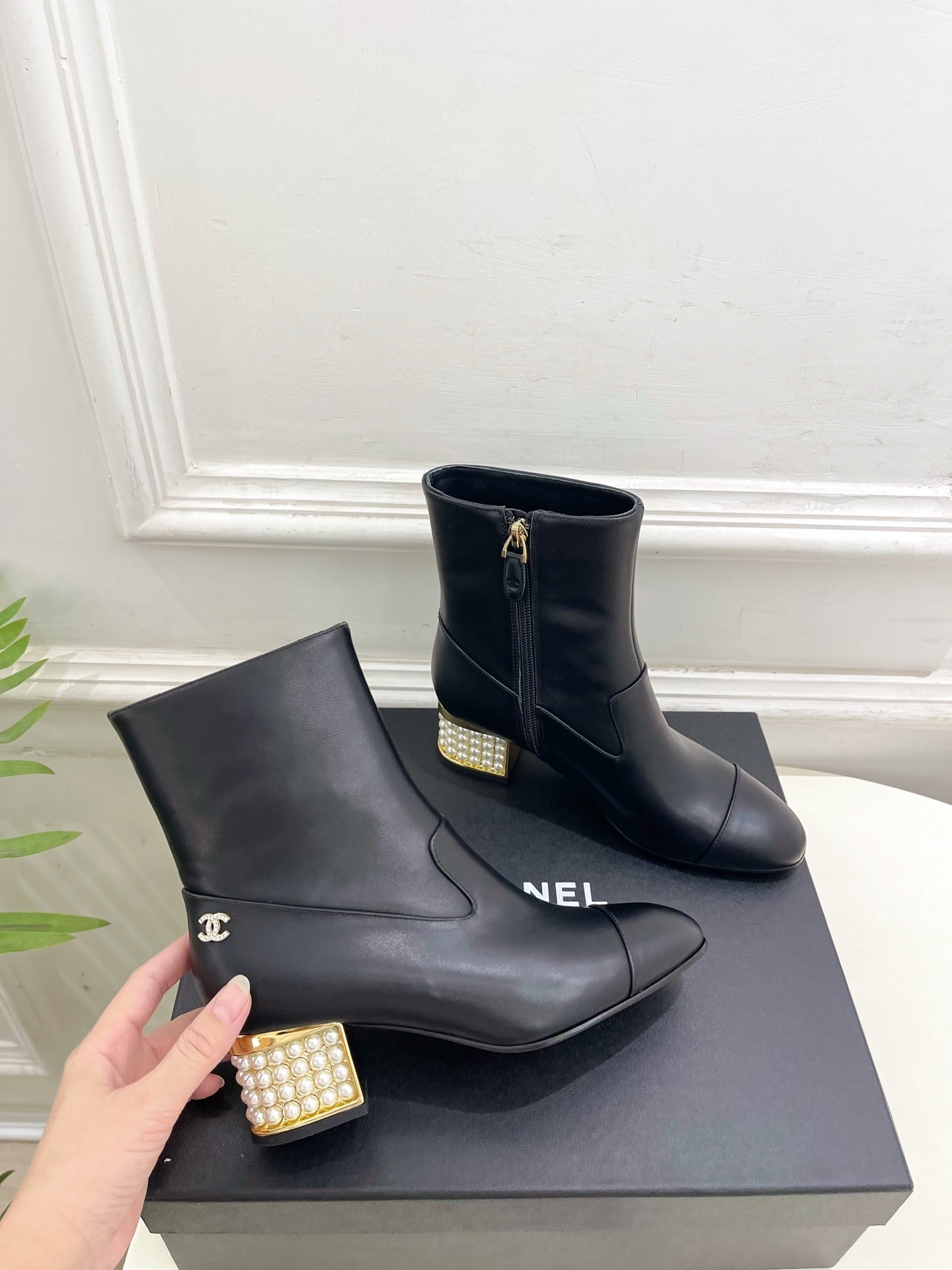 Elegant black leather ankle boots featuring a unique gold block heel decorated with rows of white pearls. - Hình 4