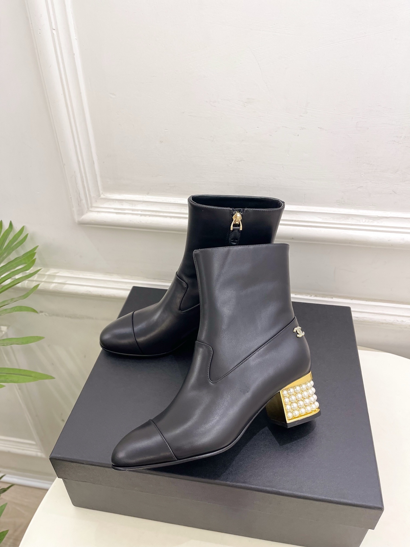 Elegant black leather ankle boots featuring a unique gold block heel decorated with rows of white pearls. - Hình 3
