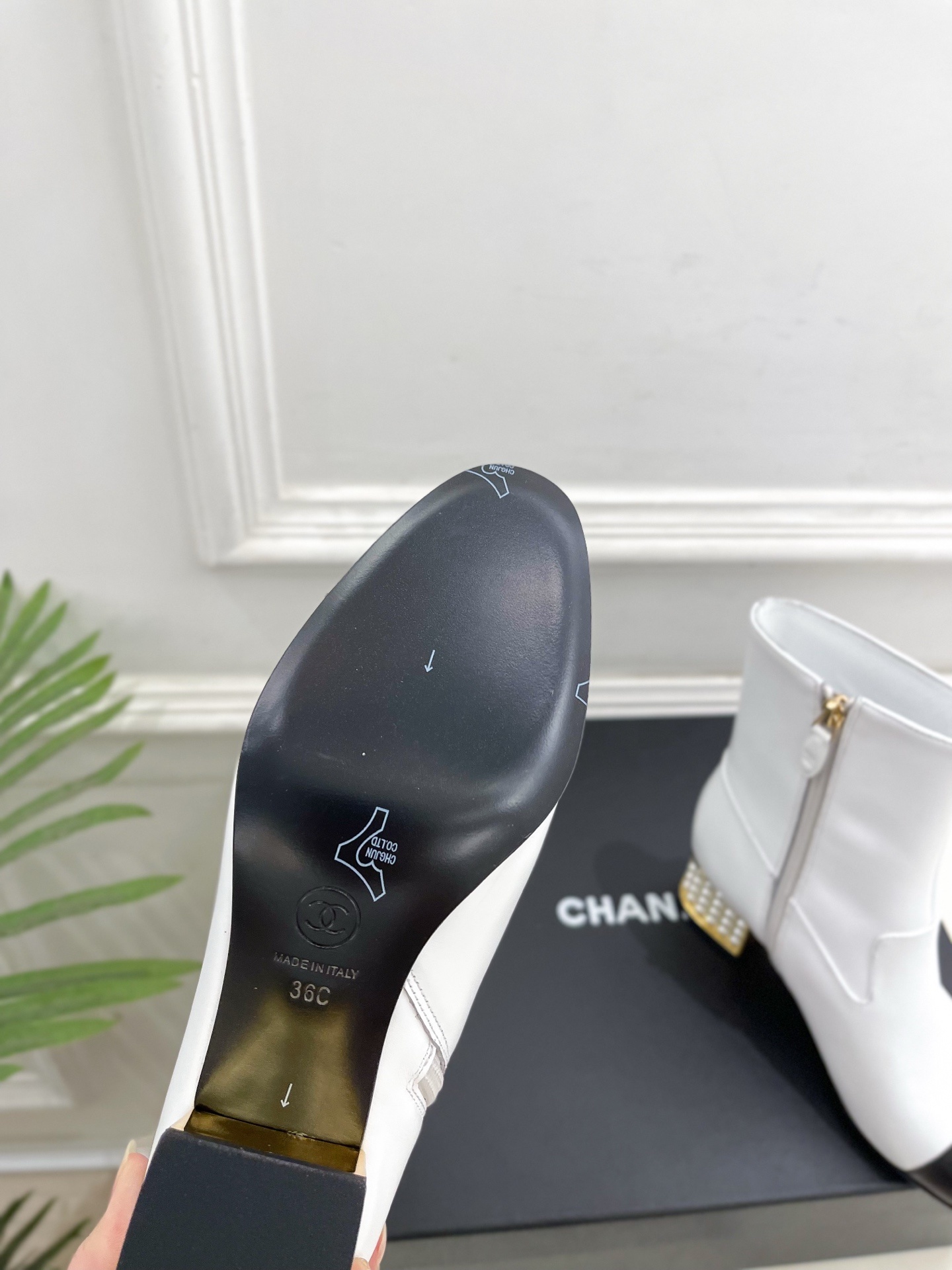 Luxury white leather ankle boots with black toe caps and gold pearl-encrusted block heels displayed on a black box. - Hình 9