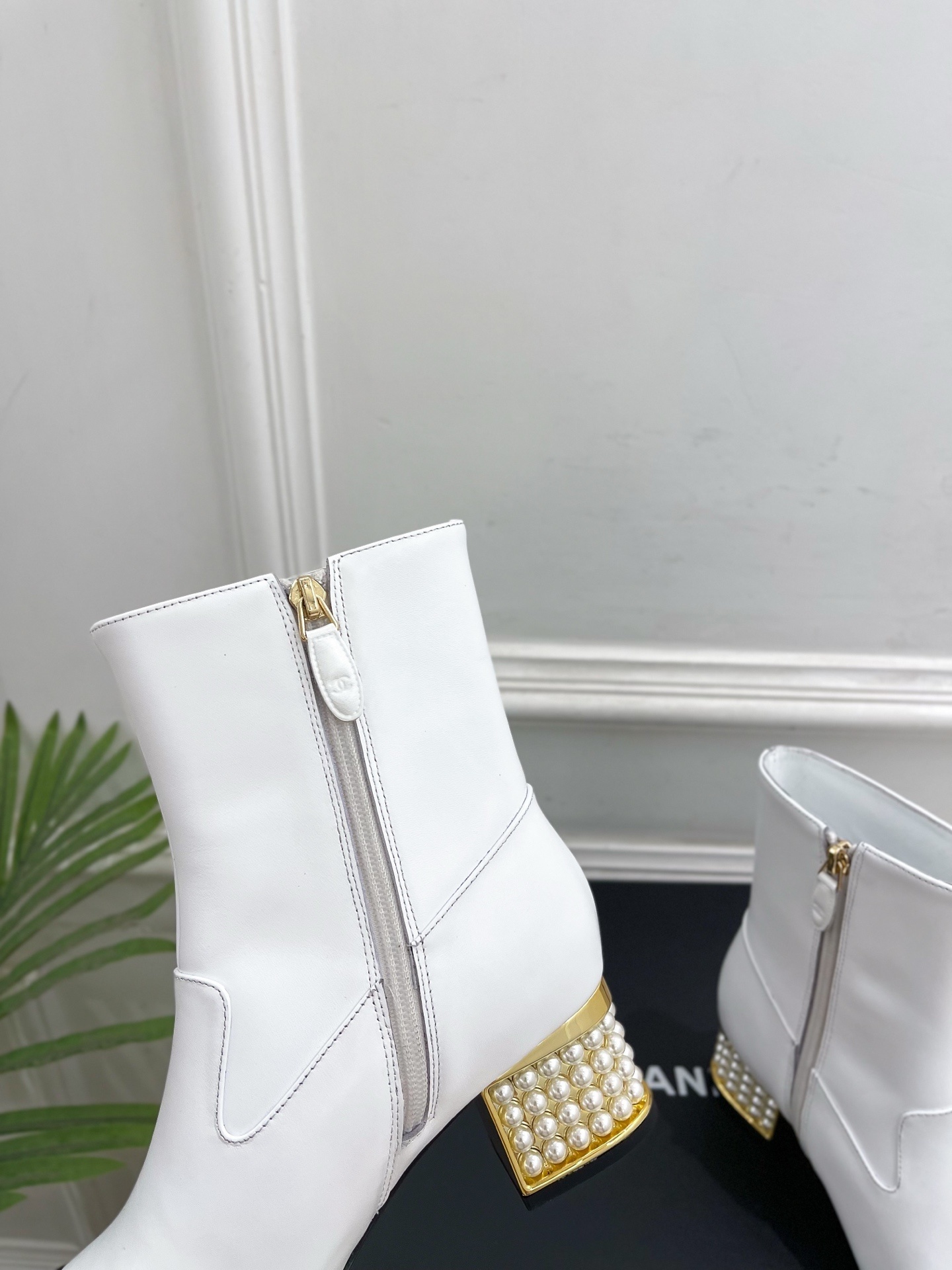 Luxury white leather ankle boots with black toe caps and gold pearl-encrusted block heels displayed on a black box. - Hình 7