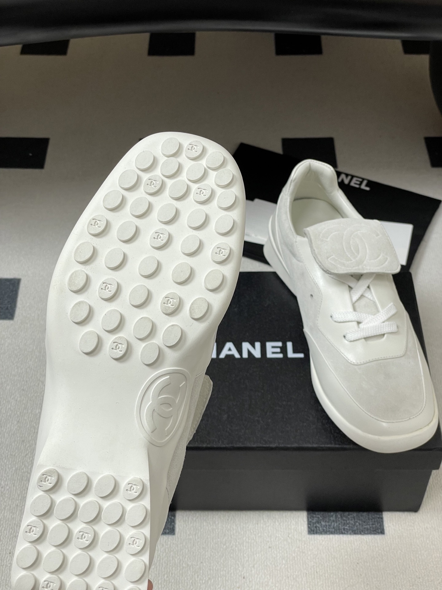 Pair of Chanel white leather and suede sneakers with embossed CC logo flap on a black surface - Hình 8