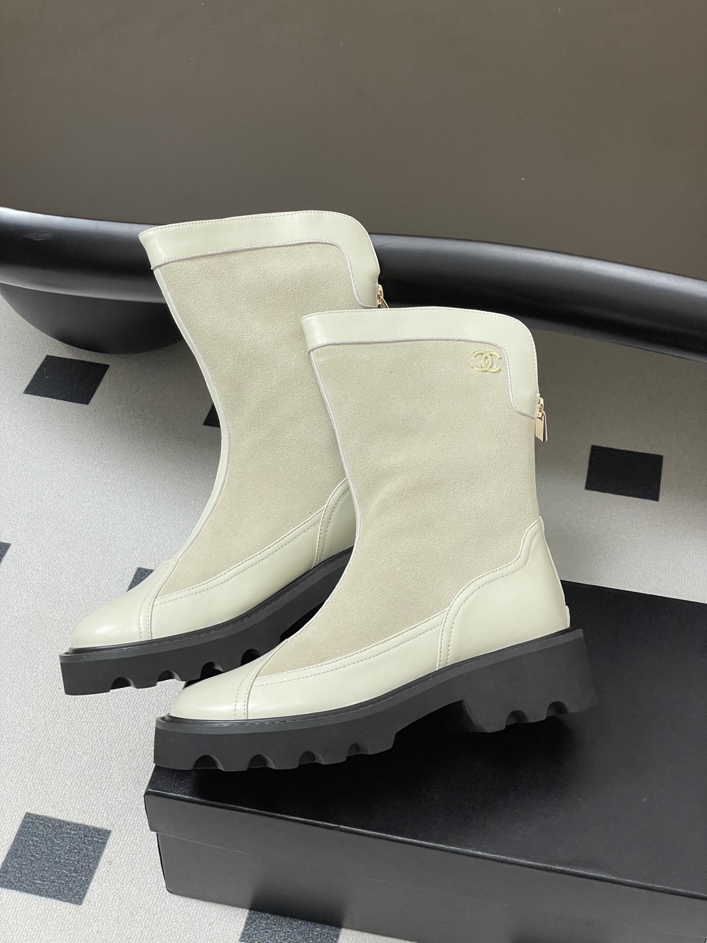 A pair of luxury Chanel off-white leather and suede mid-calf boots with thick black lug soles and gold CC logo detail. - Hình 4