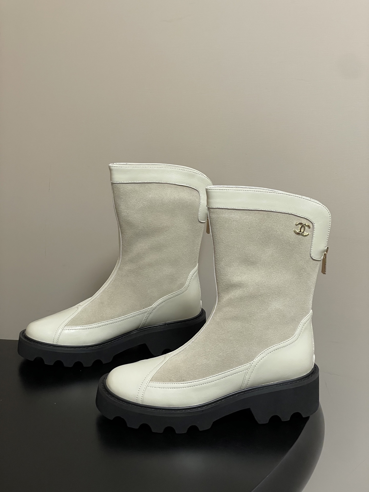 A pair of luxury Chanel off-white leather and suede mid-calf boots with thick black lug soles and gold CC logo detail. - Hình 3