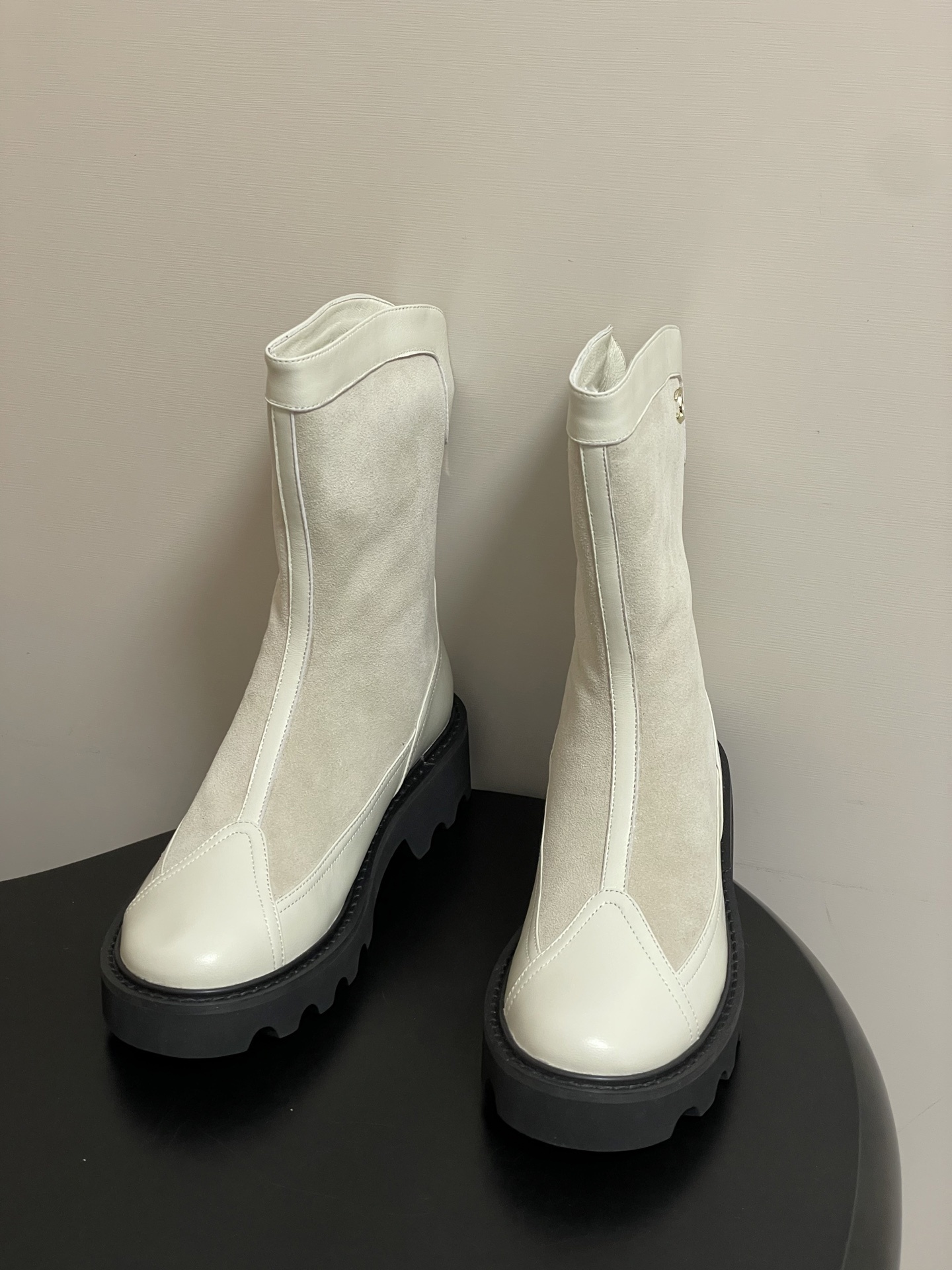 A pair of luxury Chanel off-white leather and suede mid-calf boots with thick black lug soles and gold CC logo detail. - Hình 2