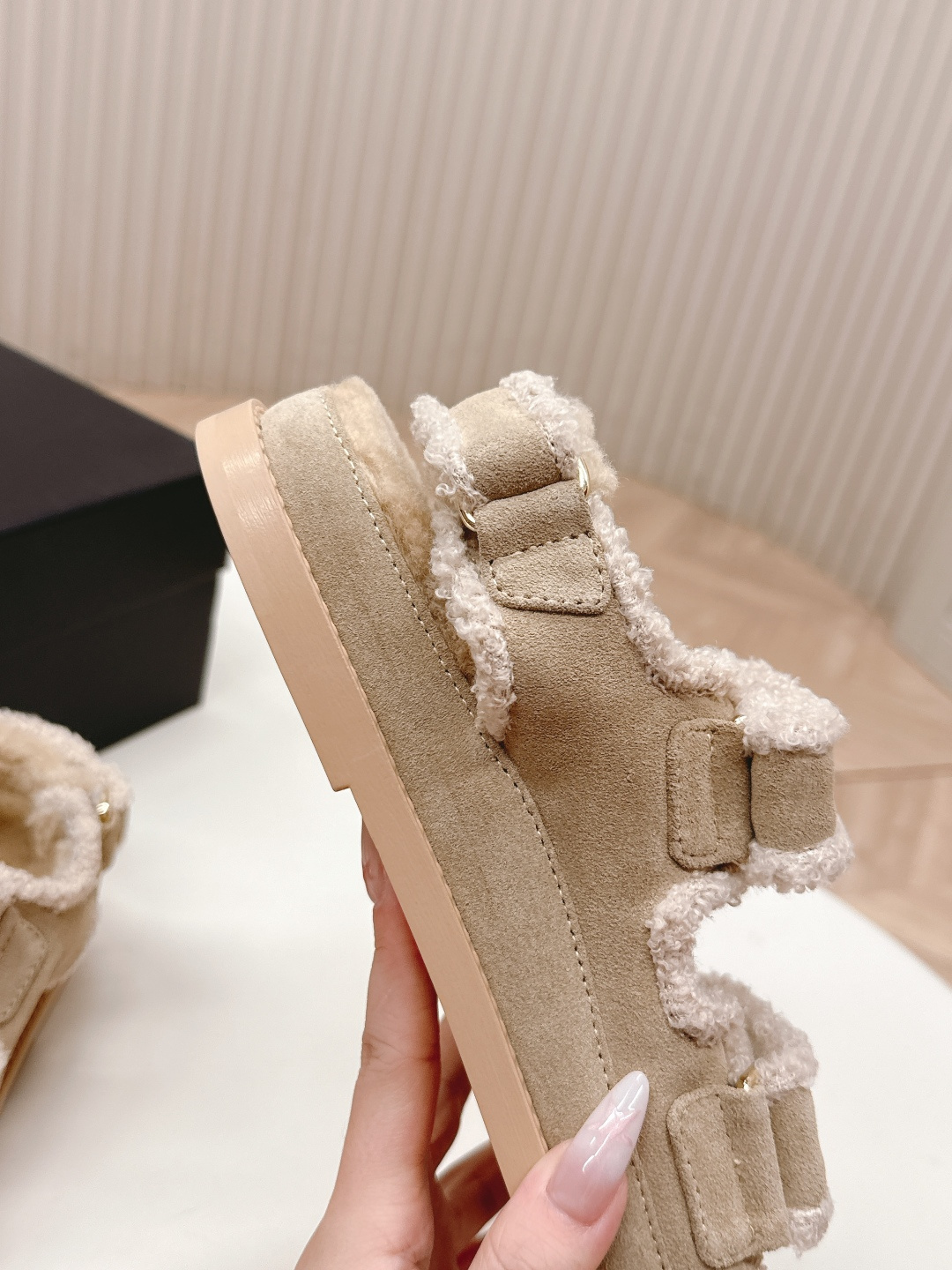 A pair of Chanel beige shearling dad sandals with gold CC logo buttons next to a black Chanel box. - Hình 6