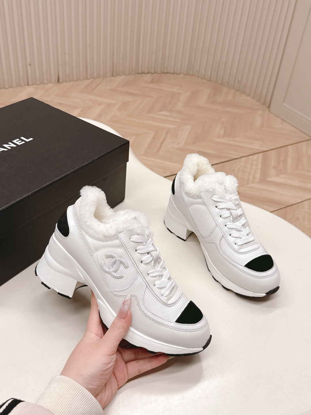 A pair of luxury Chanel white platform sneakers with plush fur lining and black toe caps displayed on a white surface. - Hình 8