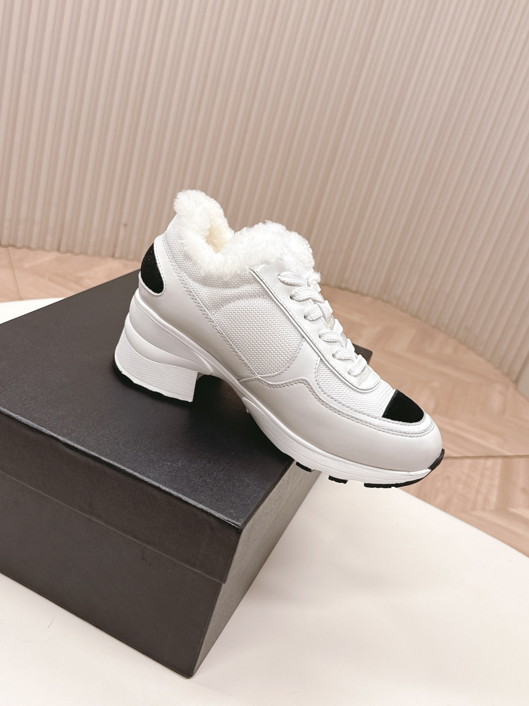A pair of luxury Chanel white platform sneakers with plush fur lining and black toe caps displayed on a white surface. - Hình 4