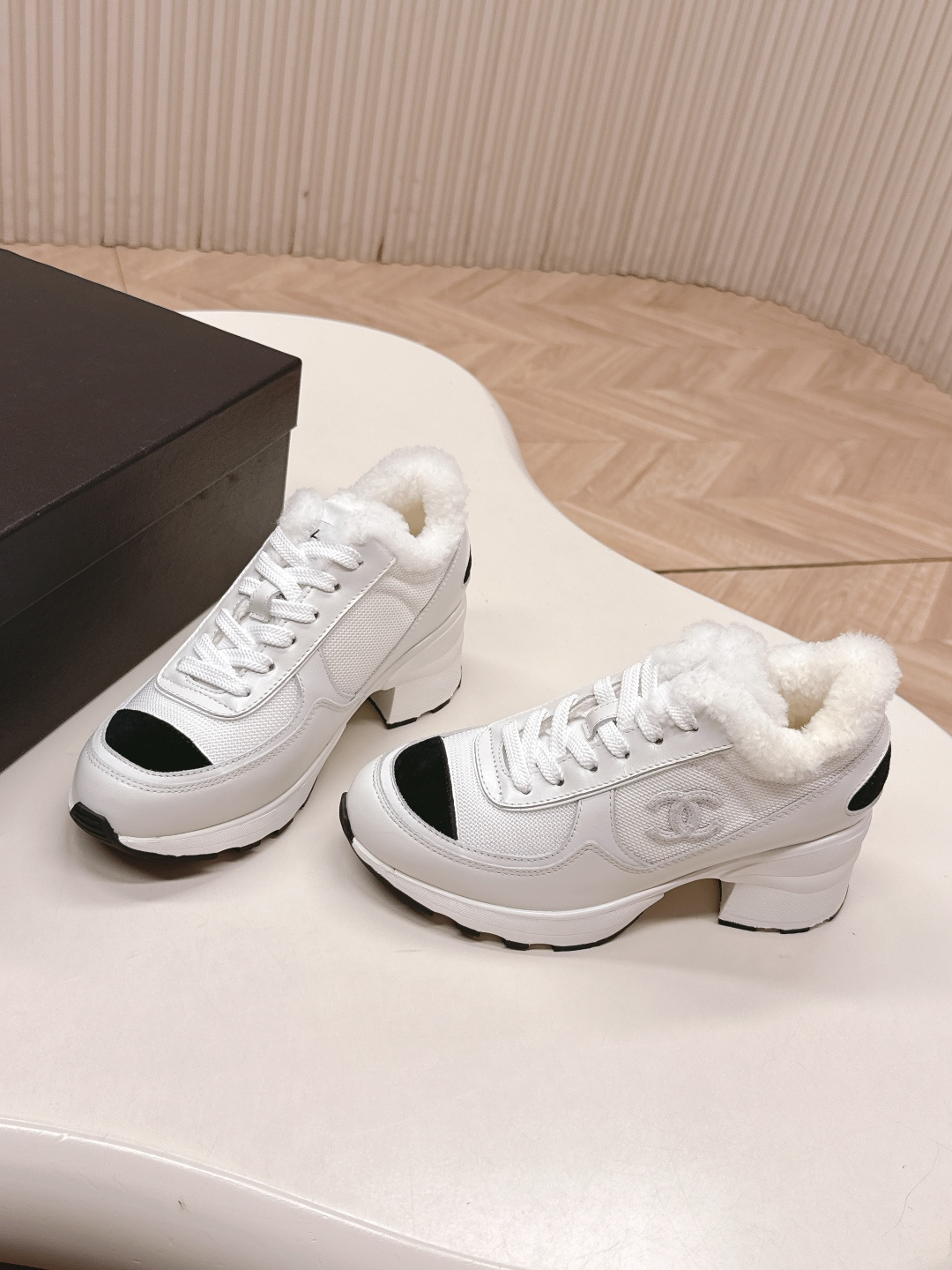 A pair of luxury Chanel white platform sneakers with plush fur lining and black toe caps displayed on a white surface. - Hình 3