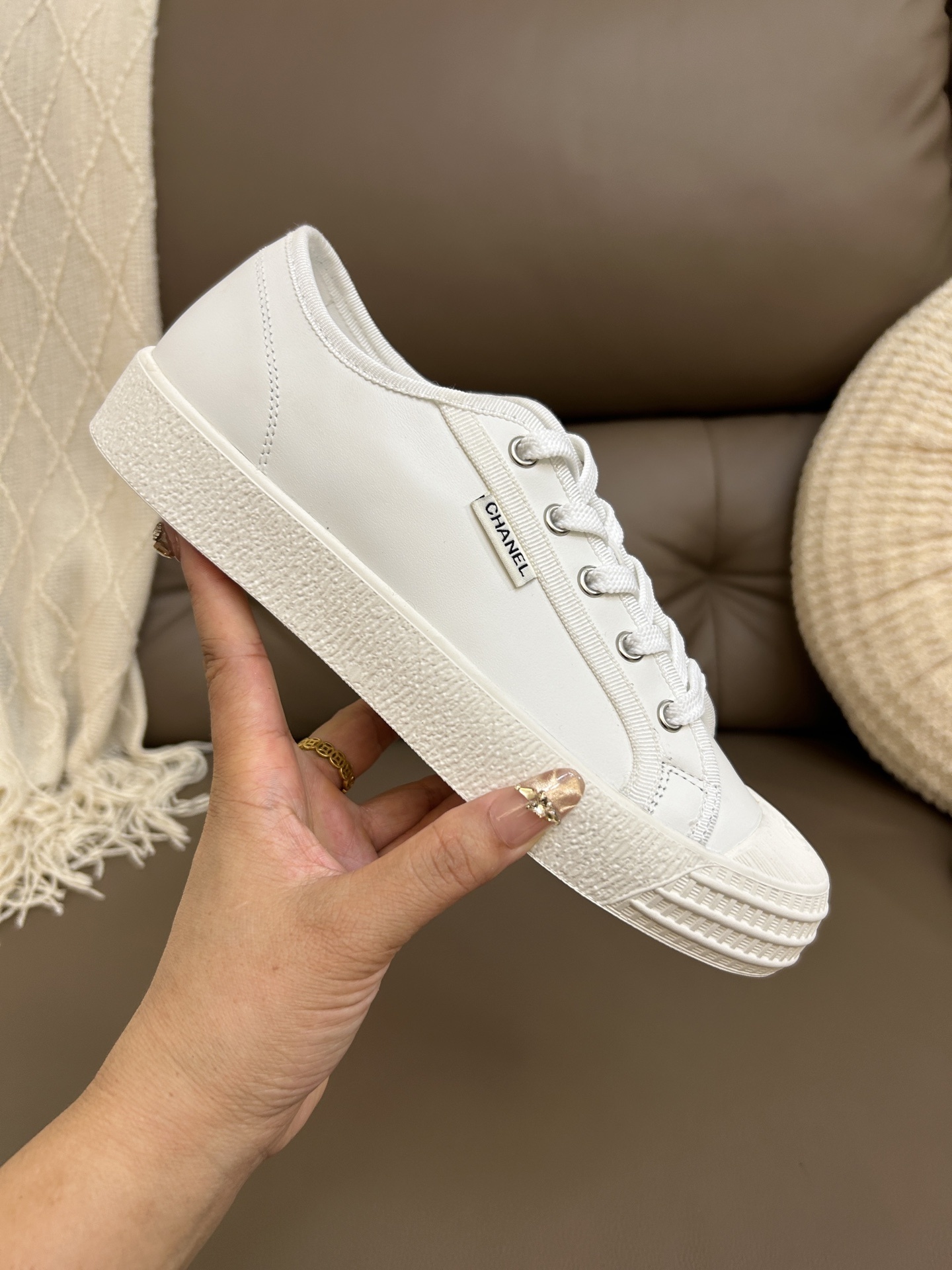 Pair of luxury Chanel white leather low-top sneakers with textured rubber toe caps featuring the CC logo. - Hình 7