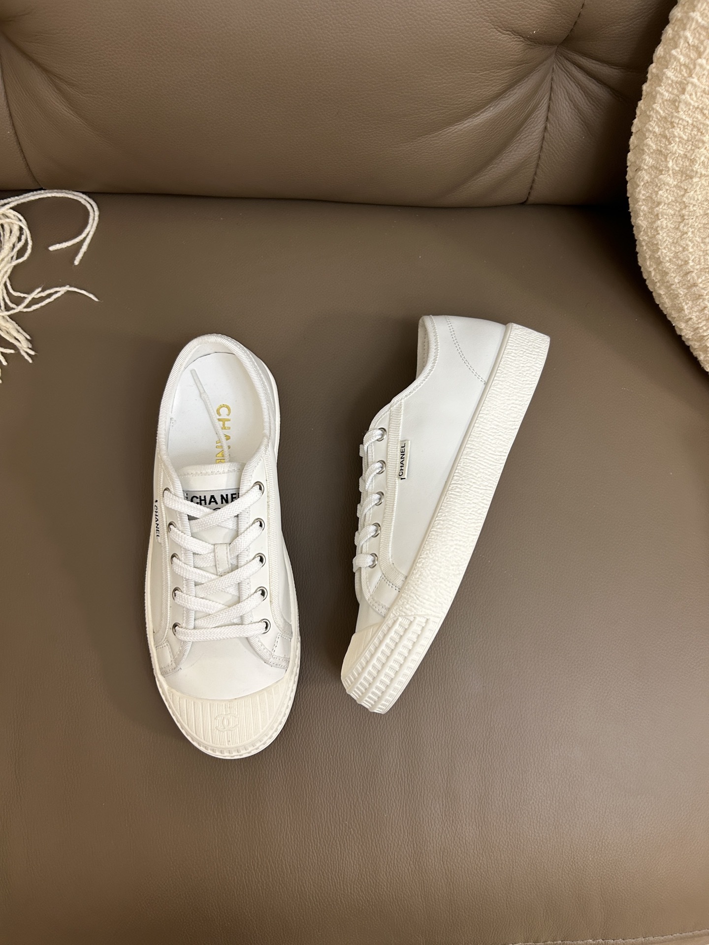 Pair of luxury Chanel white leather low-top sneakers with textured rubber toe caps featuring the CC logo. - Hình 5