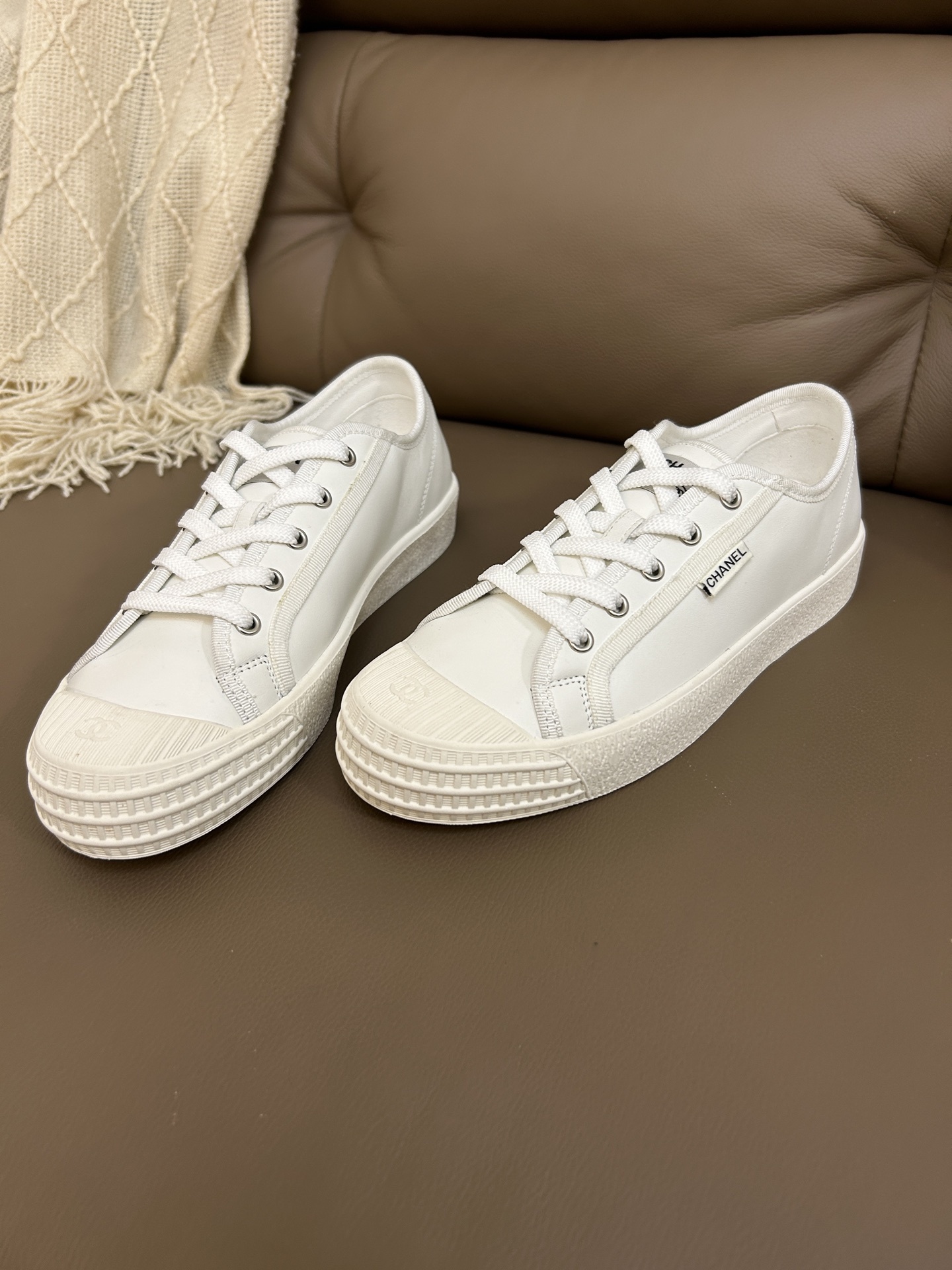 Pair of luxury Chanel white leather low-top sneakers with textured rubber toe caps featuring the CC logo. - Hình 4