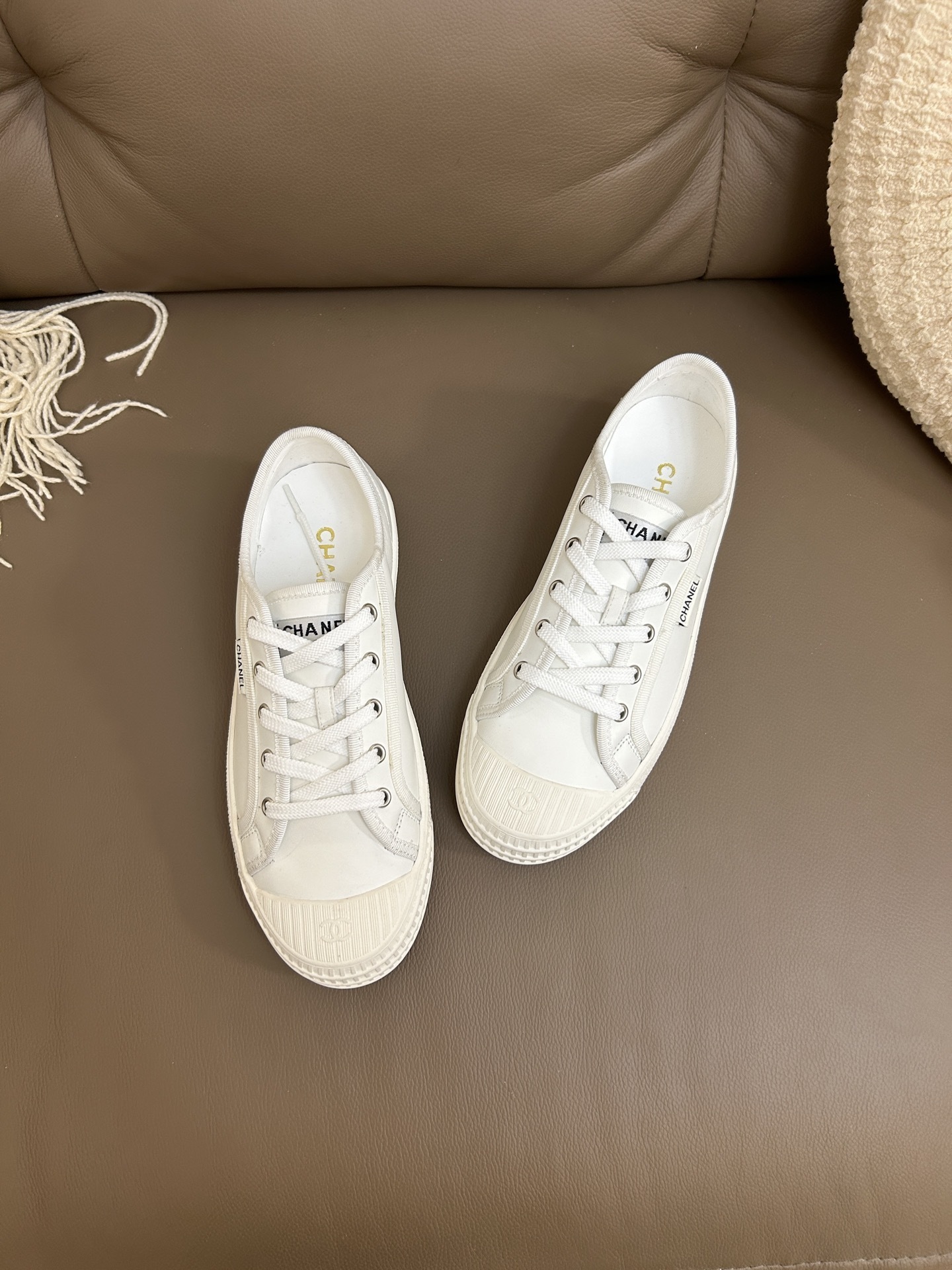 Pair of luxury Chanel white leather low-top sneakers with textured rubber toe caps featuring the CC logo. - Hình 2