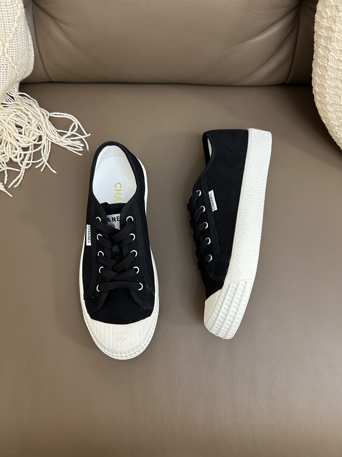A pair of black Chanel canvas low-top sneakers with white rubber toe caps and soles featuring the CC logo. - Hình 2