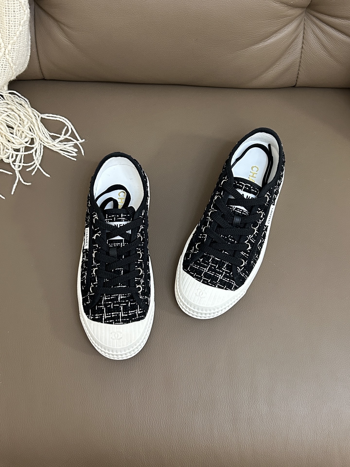 Top view of a pair of Chanel black and white tweed low-top sneakers with white rubber toe caps and CC logo. - Hình 2