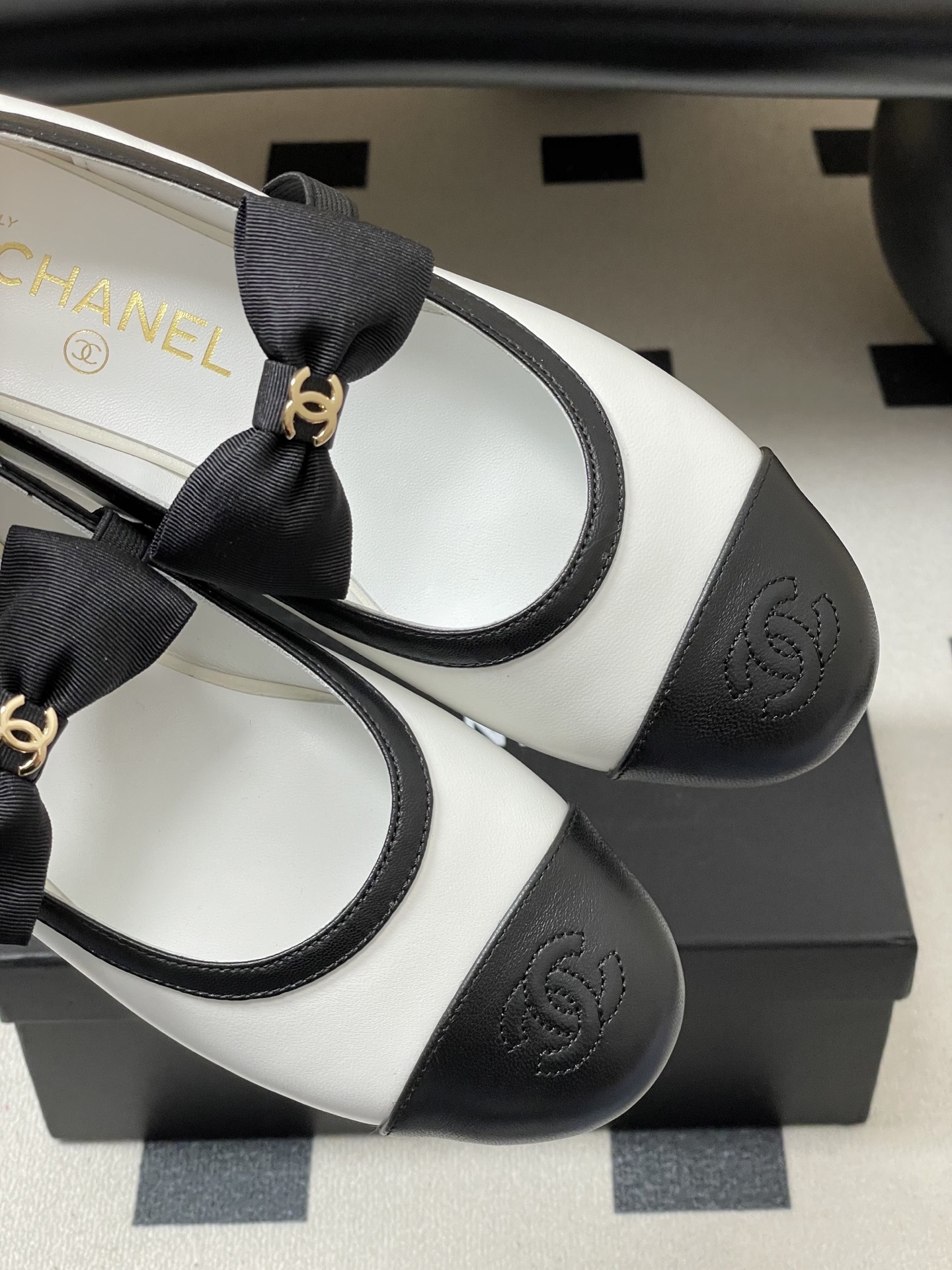 Luxury Chanel white and black leather Mary Jane flats featuring a black bow with gold logo and embroidered cap toe. - Hình 9