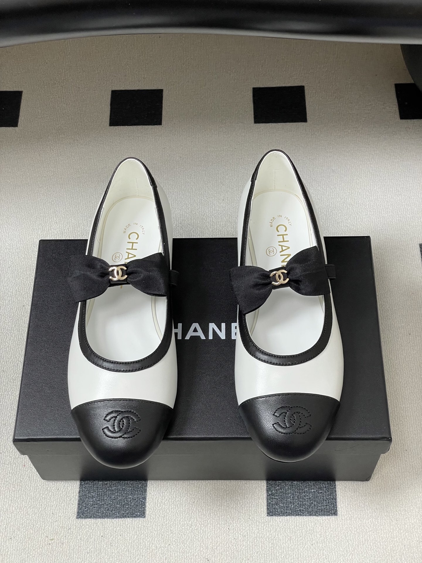 Luxury Chanel white and black leather Mary Jane flats featuring a black bow with gold logo and embroidered cap toe. - Hình 5