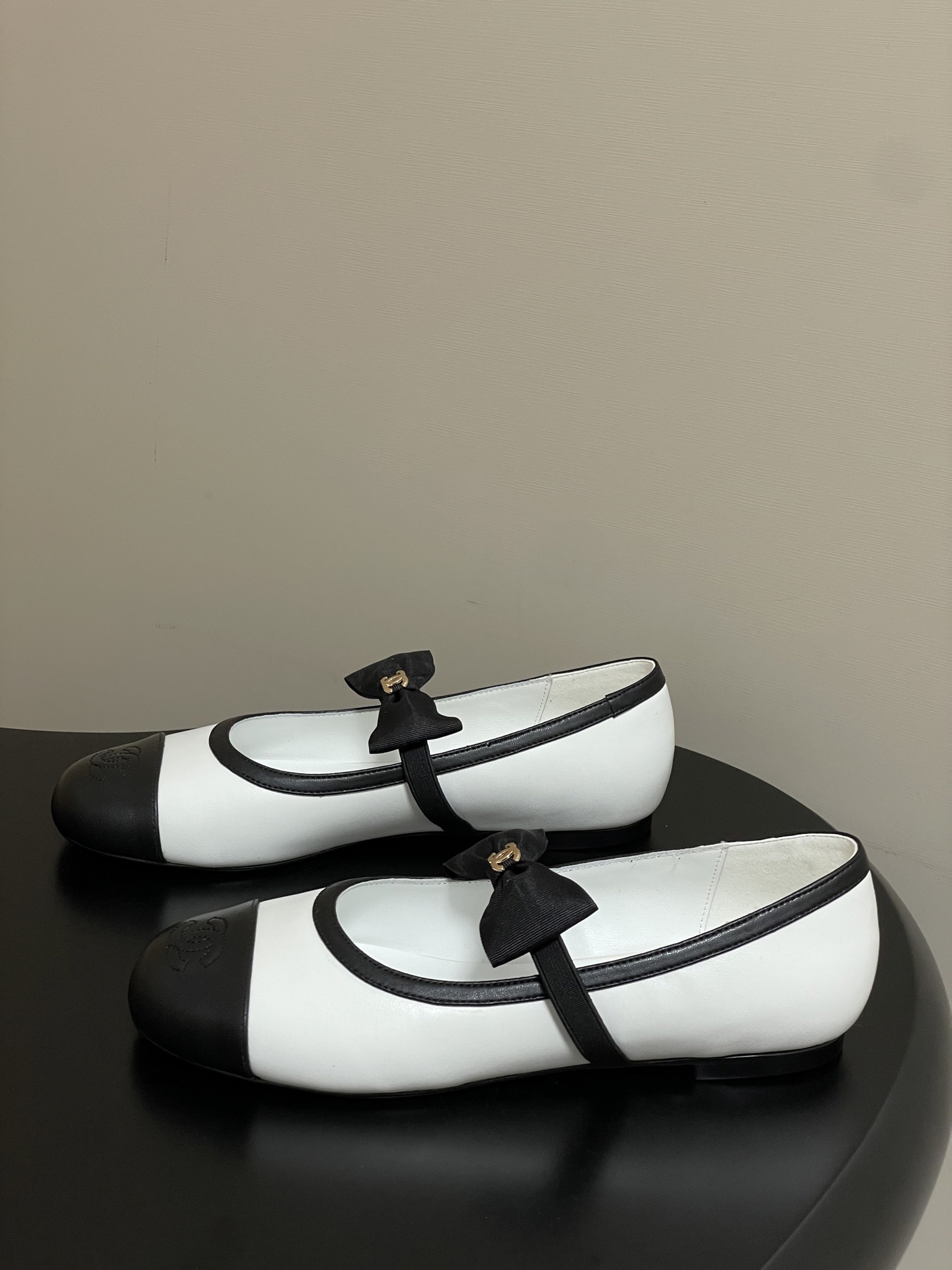 Luxury Chanel white and black leather Mary Jane flats featuring a black bow with gold logo and embroidered cap toe. - Hình 3