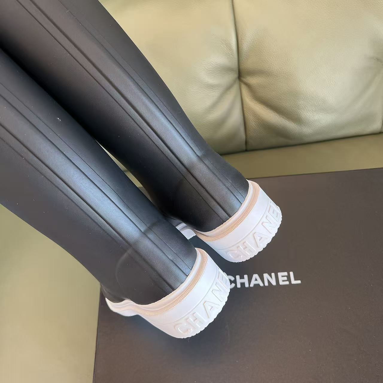 Pair of black Chanel rubber rain boots with white toe caps and interlocking CC logo on a black box - Hình 8