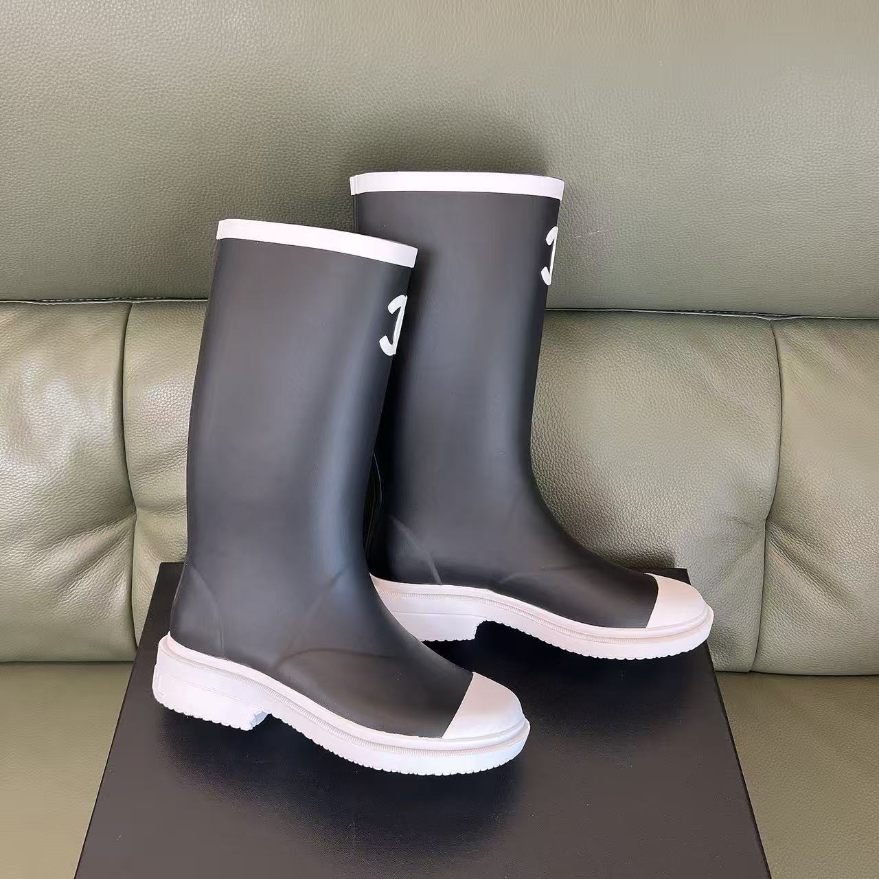 Pair of black Chanel rubber rain boots with white toe caps and interlocking CC logo on a black box - Hình 7