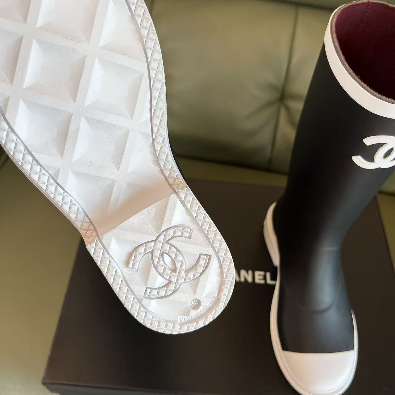 Pair of black Chanel rubber rain boots with white toe caps and interlocking CC logo on a black box - Hình 6