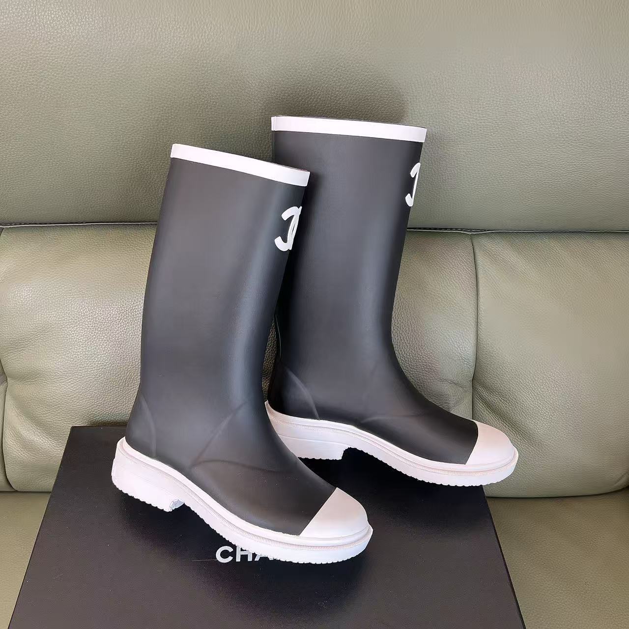 Pair of black Chanel rubber rain boots with white toe caps and interlocking CC logo on a black box - Hình 5